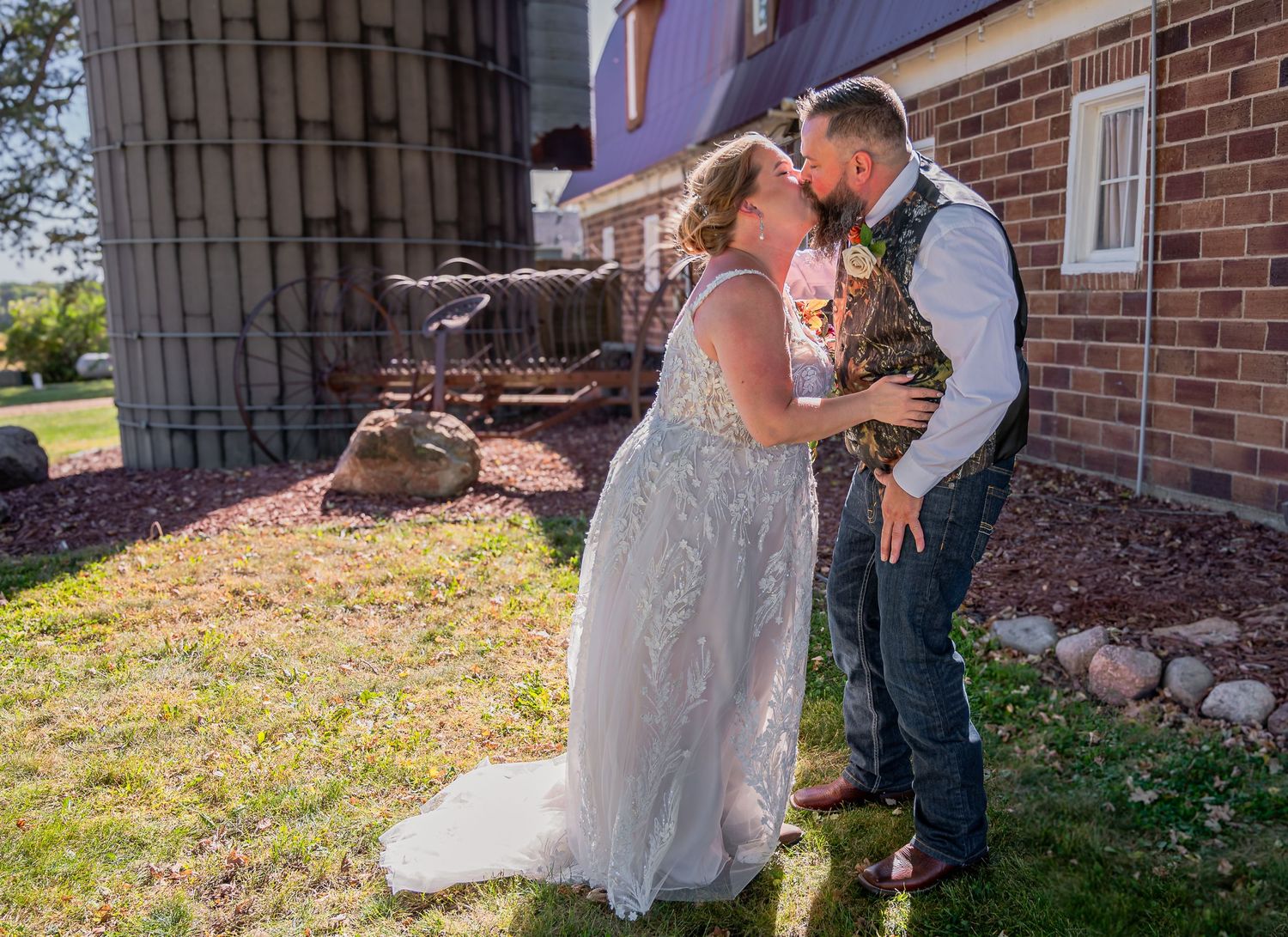 A tender wedding moment shared outside a rustic brick building on a sunny day.