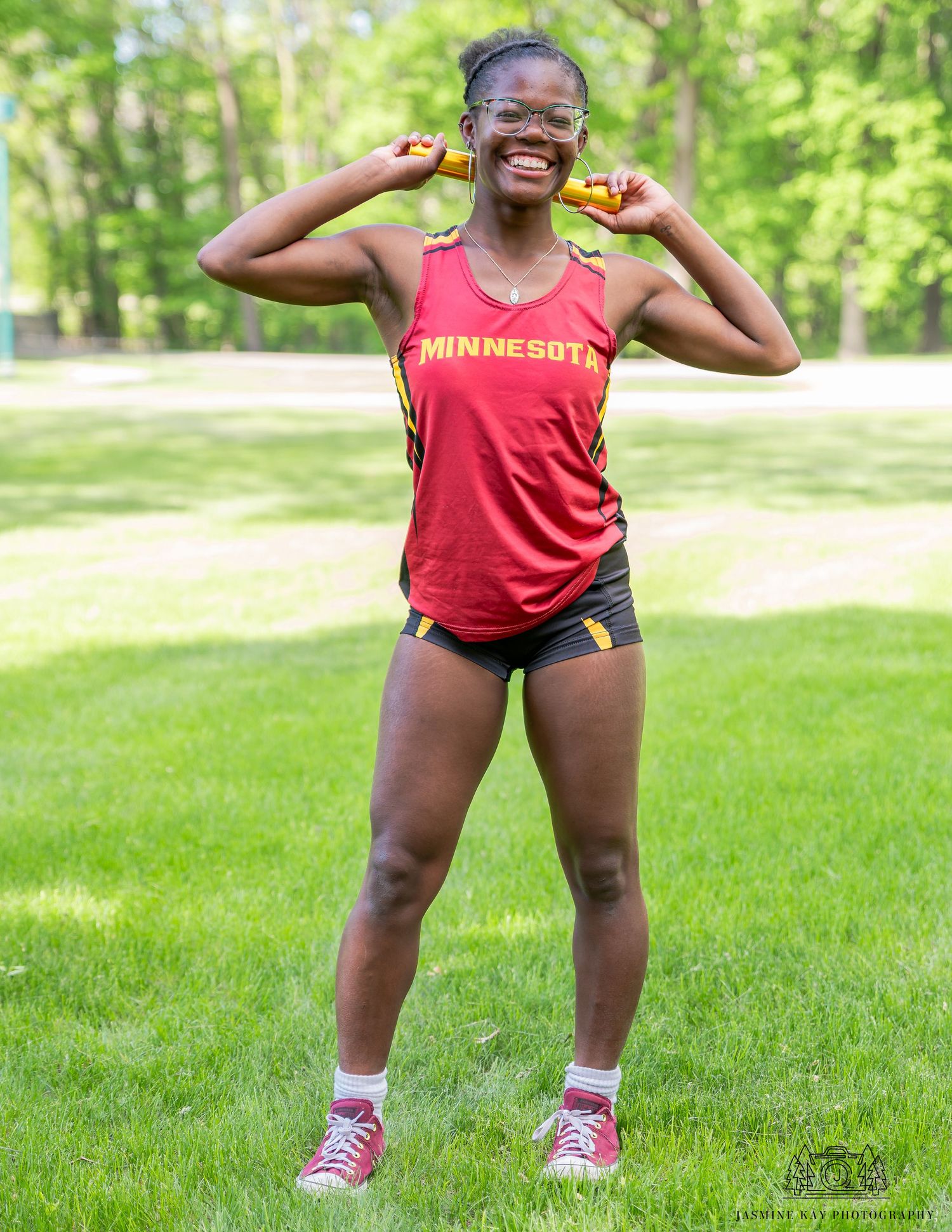 A sequence of four exercise poses showing squatting movements on green grass in a park setting.