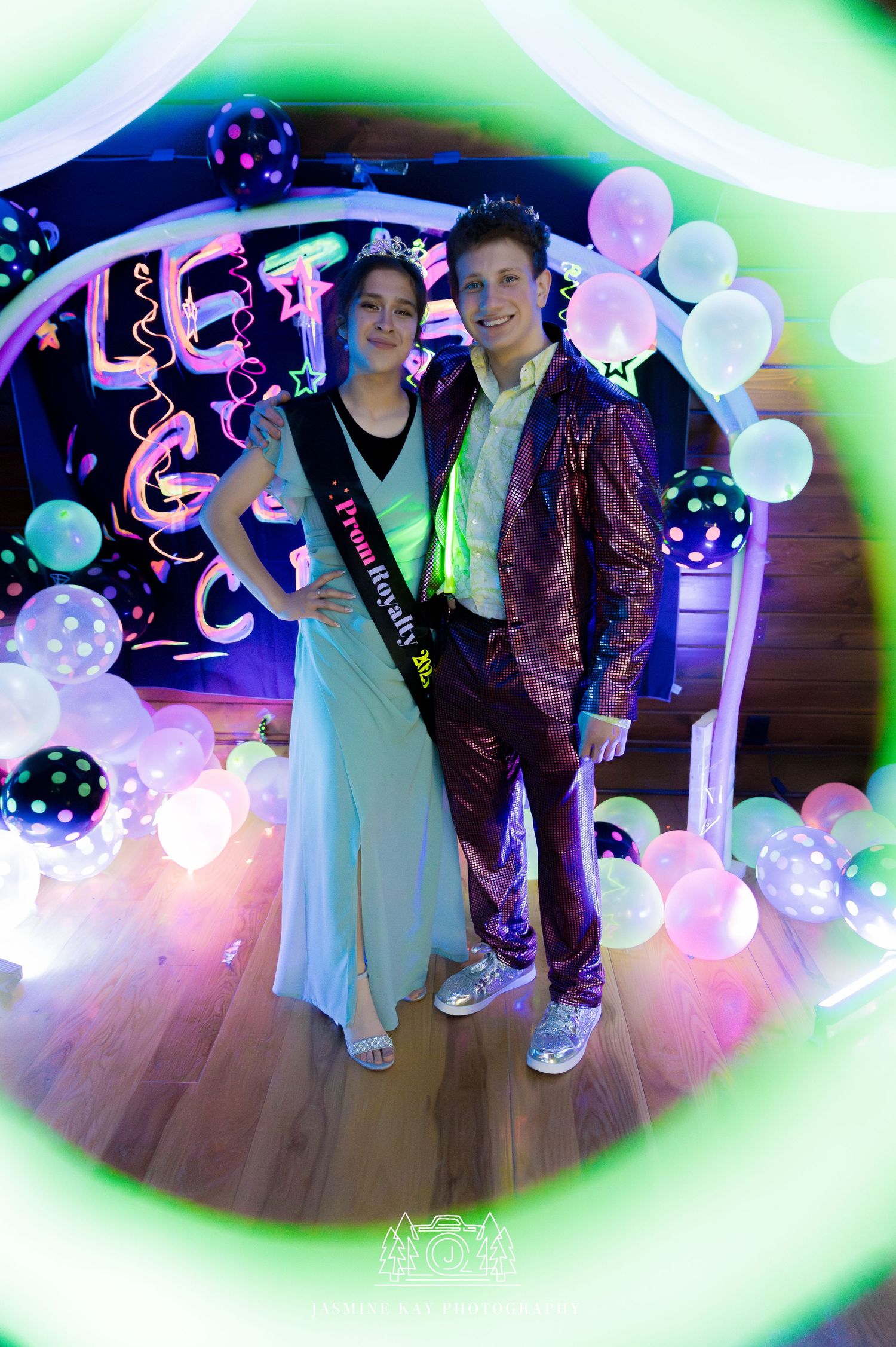Party scene with polka dot balloons and colorful lighting on a dance floor as people celebrate together.