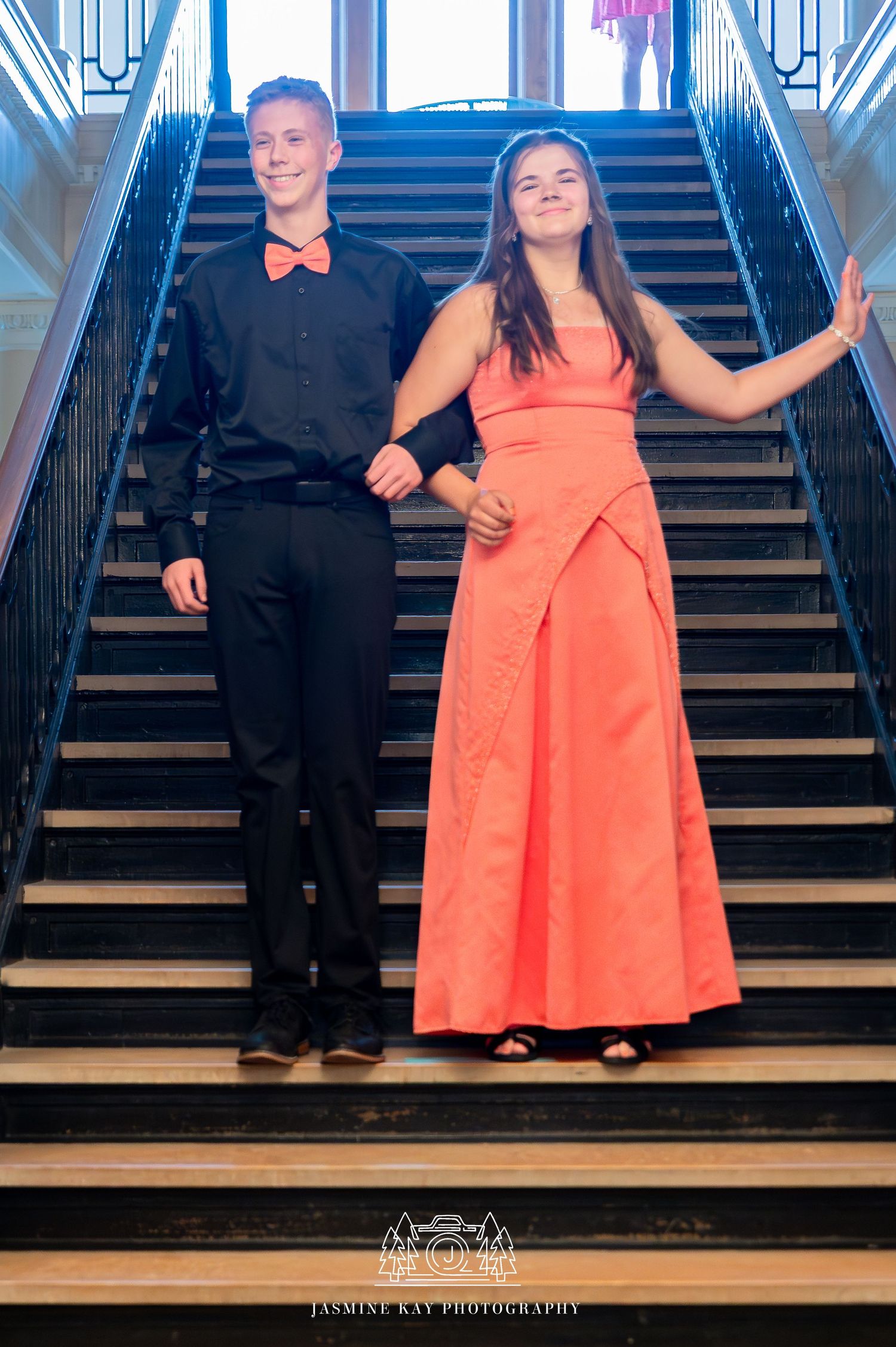A couple in formal attire poses on wooden stairs in a sequence of playful dance-like movements.