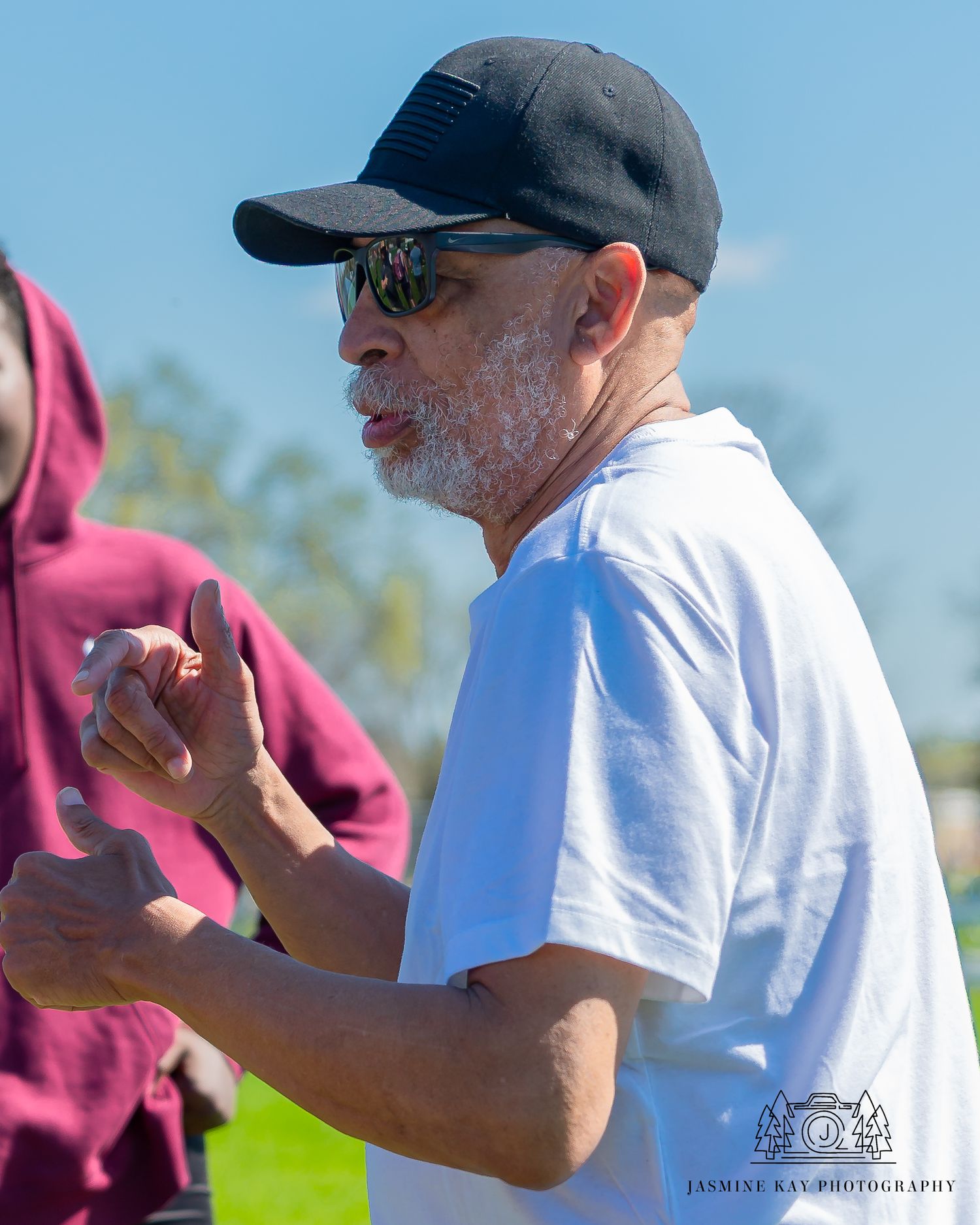 Coach demonstrating discus throwing techniques during outdoor training session.