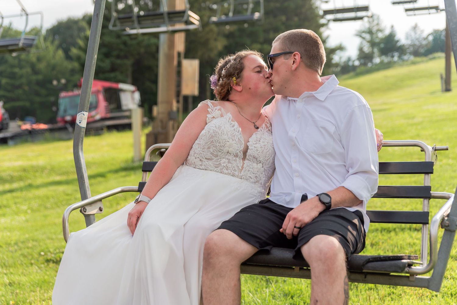 A romantic moment shared on a ski lift bench surrounded by green summer hills.