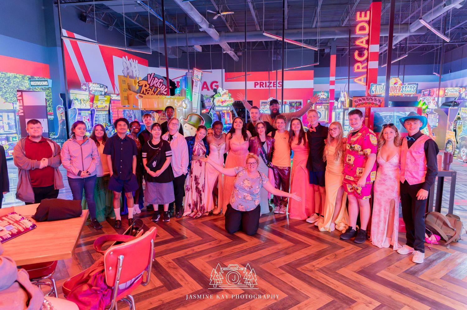 A group of people gathered in a colorful indoor space with pink lighting and chevron-patterned flooring.