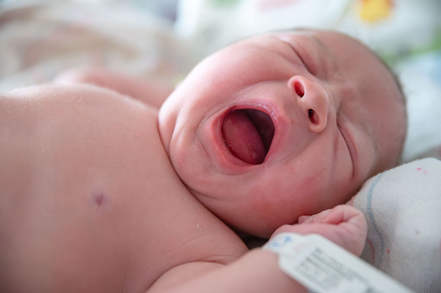 A series of close-up shots showing a newborn baby's expressions, yawning, and facial features in soft lighting.