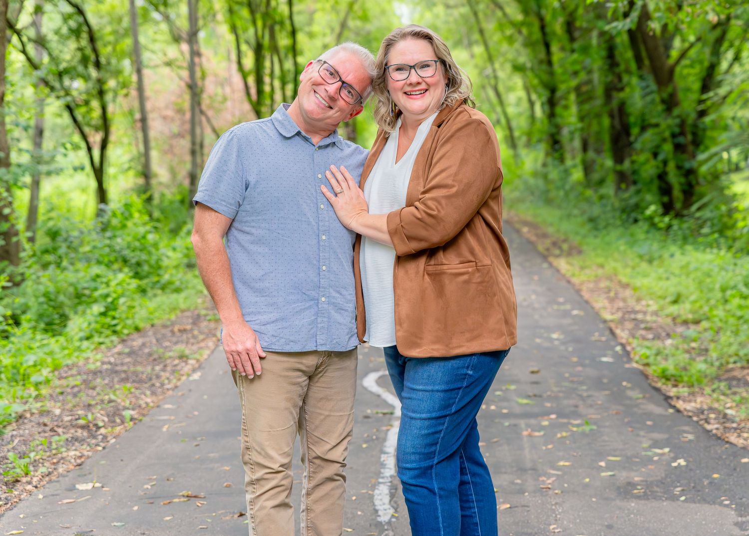 Couple sharing a joyful moment while walking together on a tree-lined path during autumn.