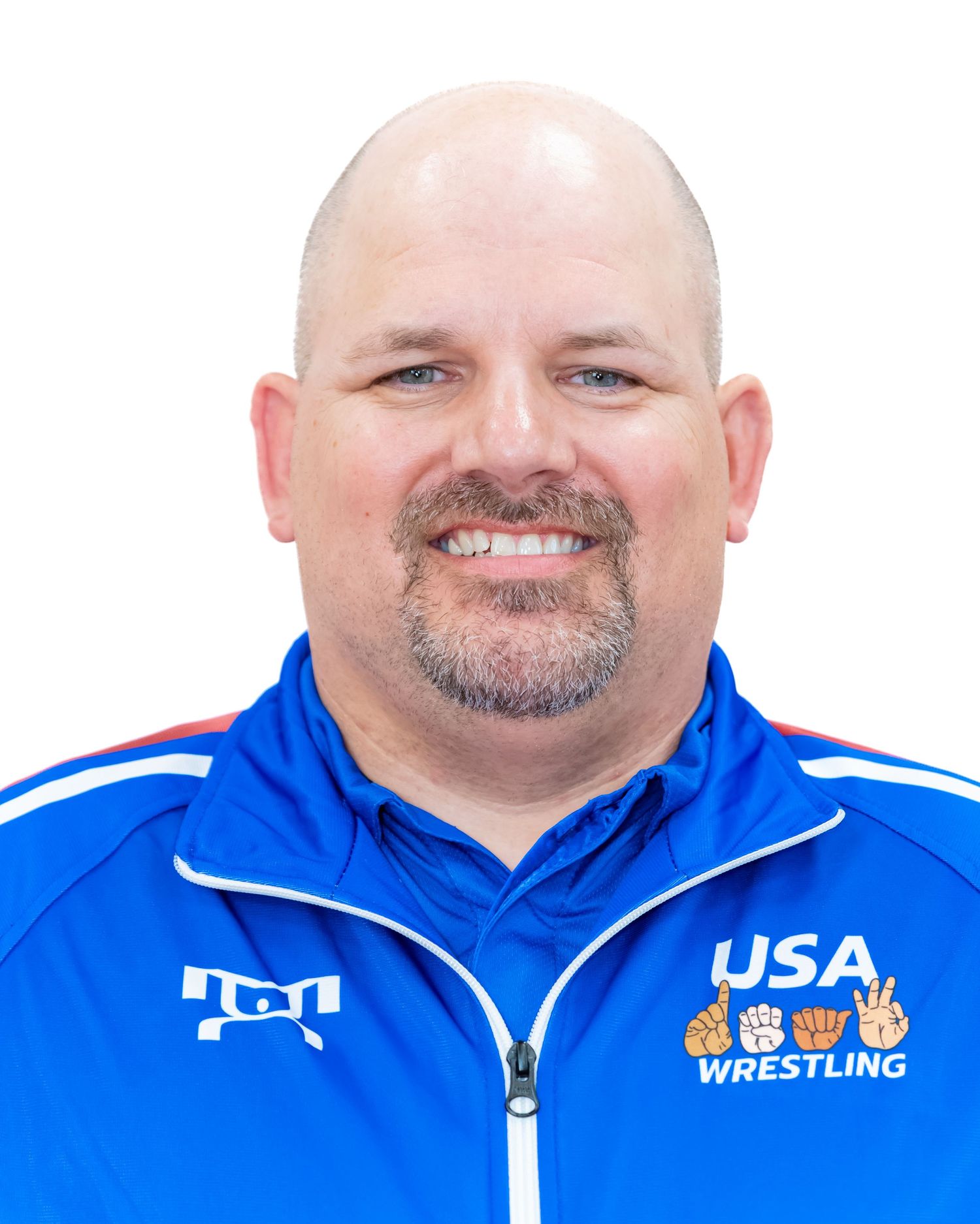 Portrait of a coach in USA Wrestling blue jacket with gray facial hair and friendly expression.