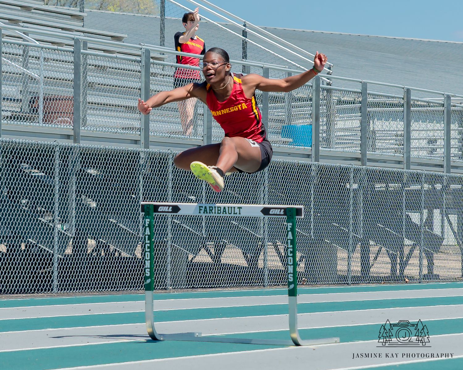 Athletic figure performs a dynamic long jump sequence on a blue track surface.