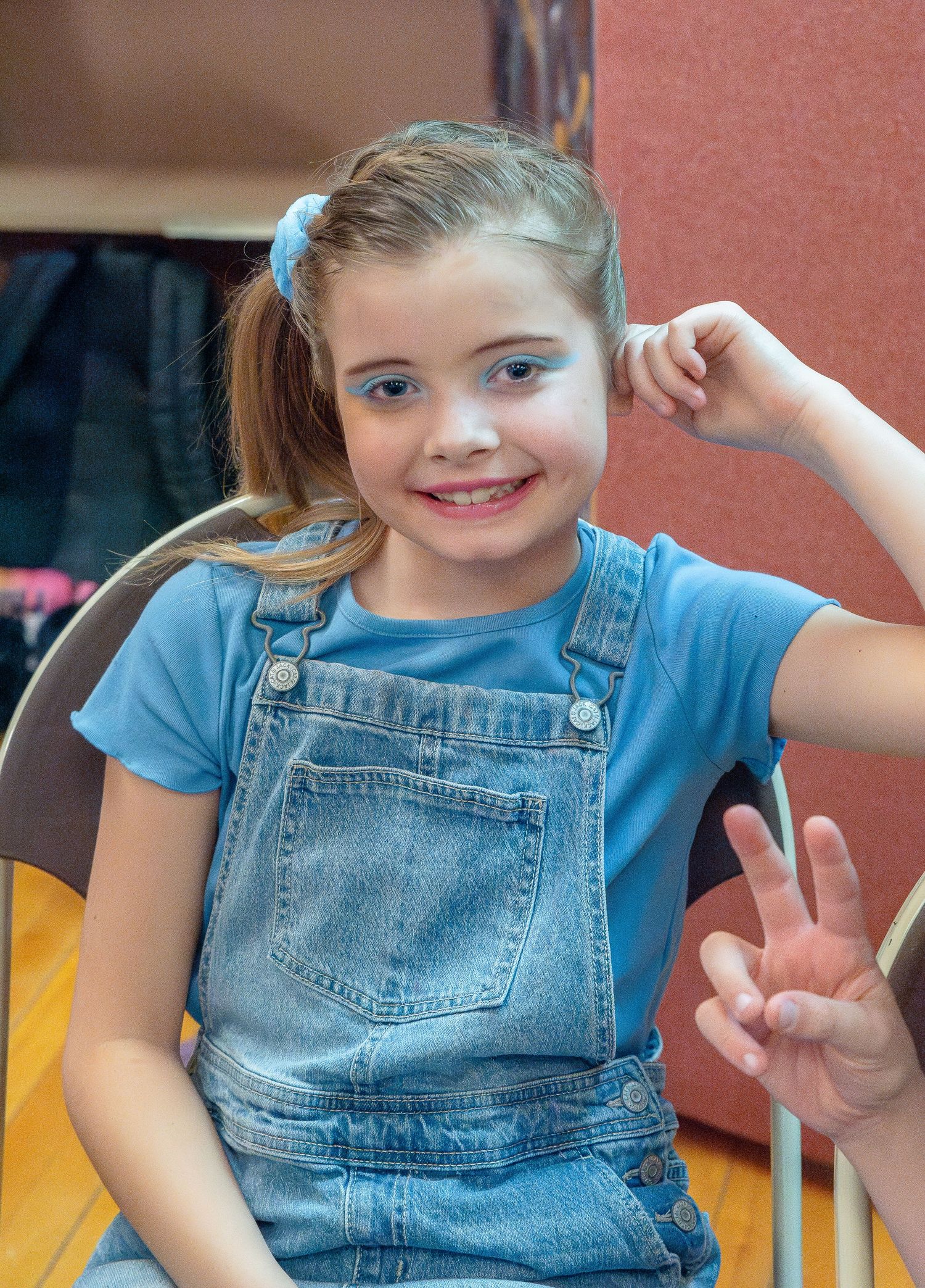 A series of seven sequential photos showing a child in denim overalls and blue shirt making playful expressions.