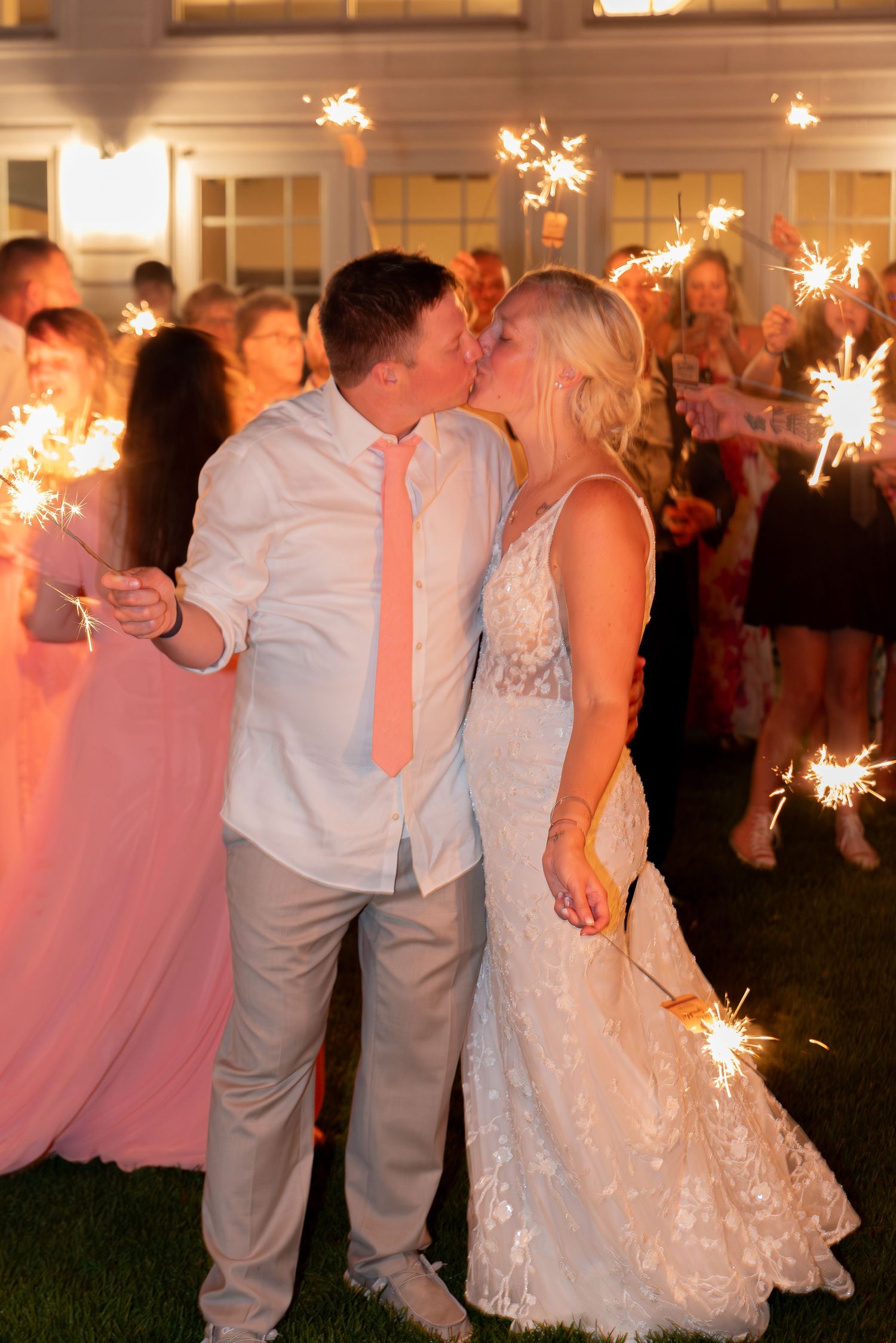 Wedding celebration with sparklers as couple shares romantic moment.