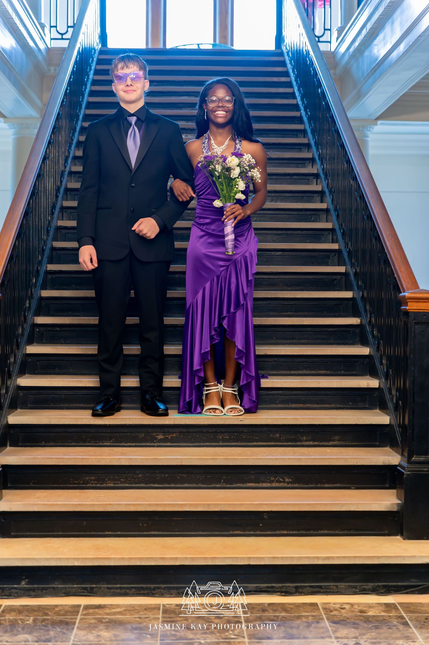 A couple in formal attire poses on wooden stairs in a sequence of four similar photos.