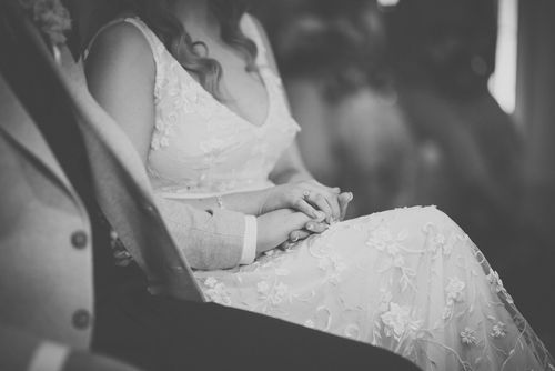 Black and white detail shot of intricate lace patterns on a wedding dress.