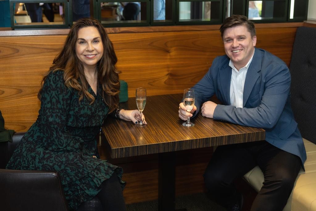 Two people enjoying drinks while seated at a wooden table in an upscale dining establishment.