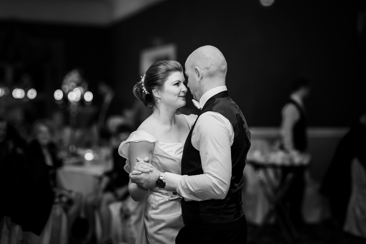 Black and white candid photographs of wedding guests dancing and celebrating at a formal reception.