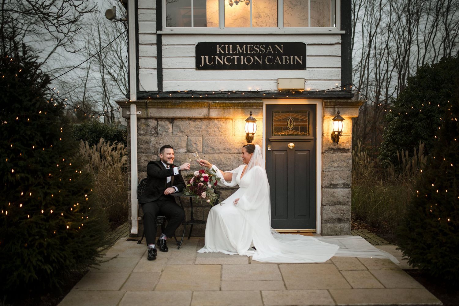 Elegant winter wedding scene at Kilmenon Hunt Foundation with a couple sitting on stone steps at dusk.
