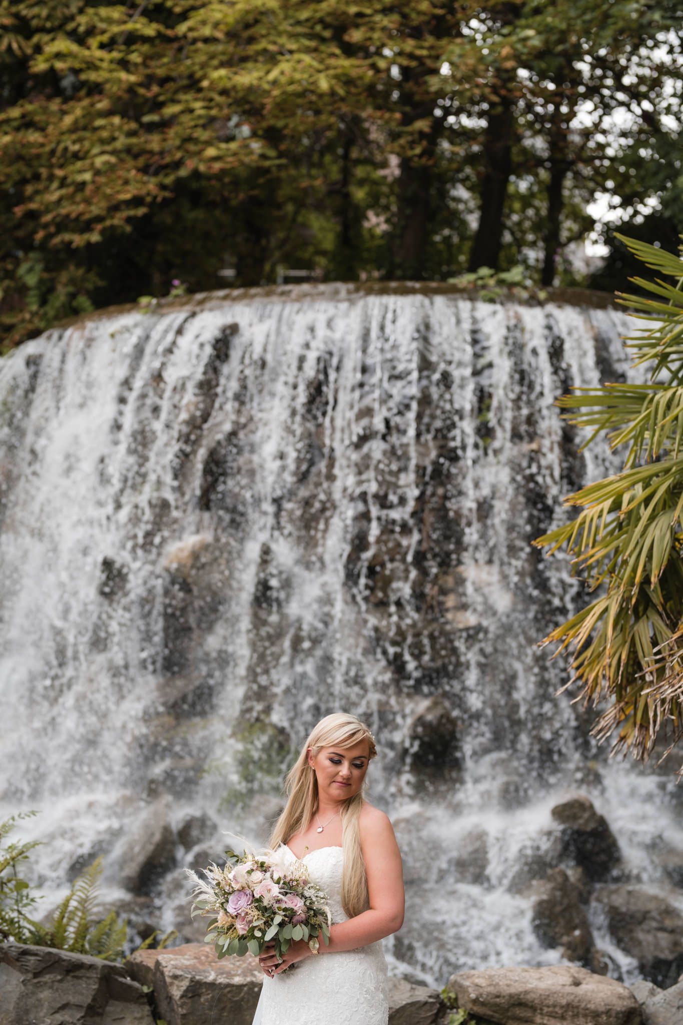 Stunning bridal portrait by a cascading waterfall with natural scenery and peaceful water backdrop.