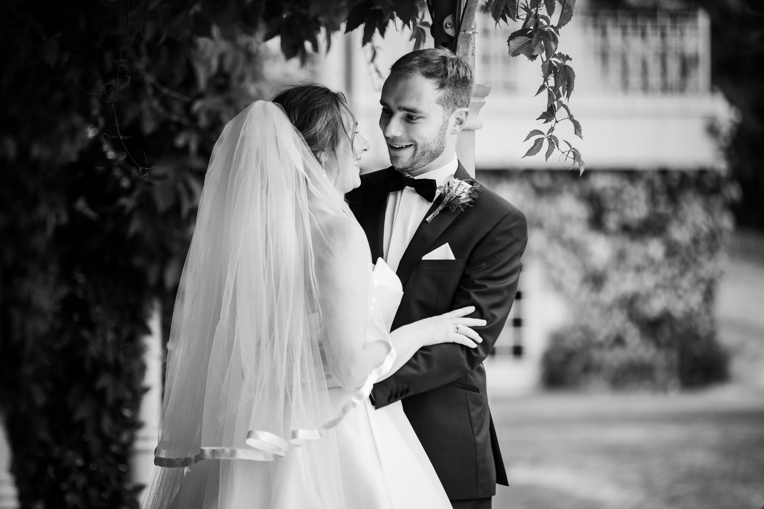 A romantic black and white wedding photo shows the couple embracing outdoors with a veil and formal attire.
