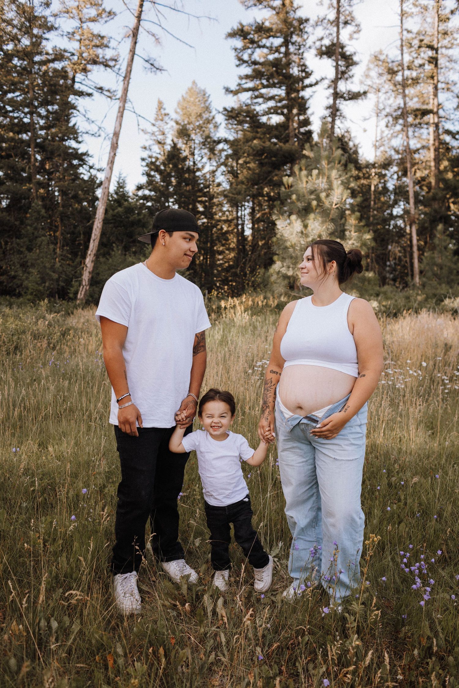 Family enjoying a warm sunset moment together in a field of tall grass and wildflowers.