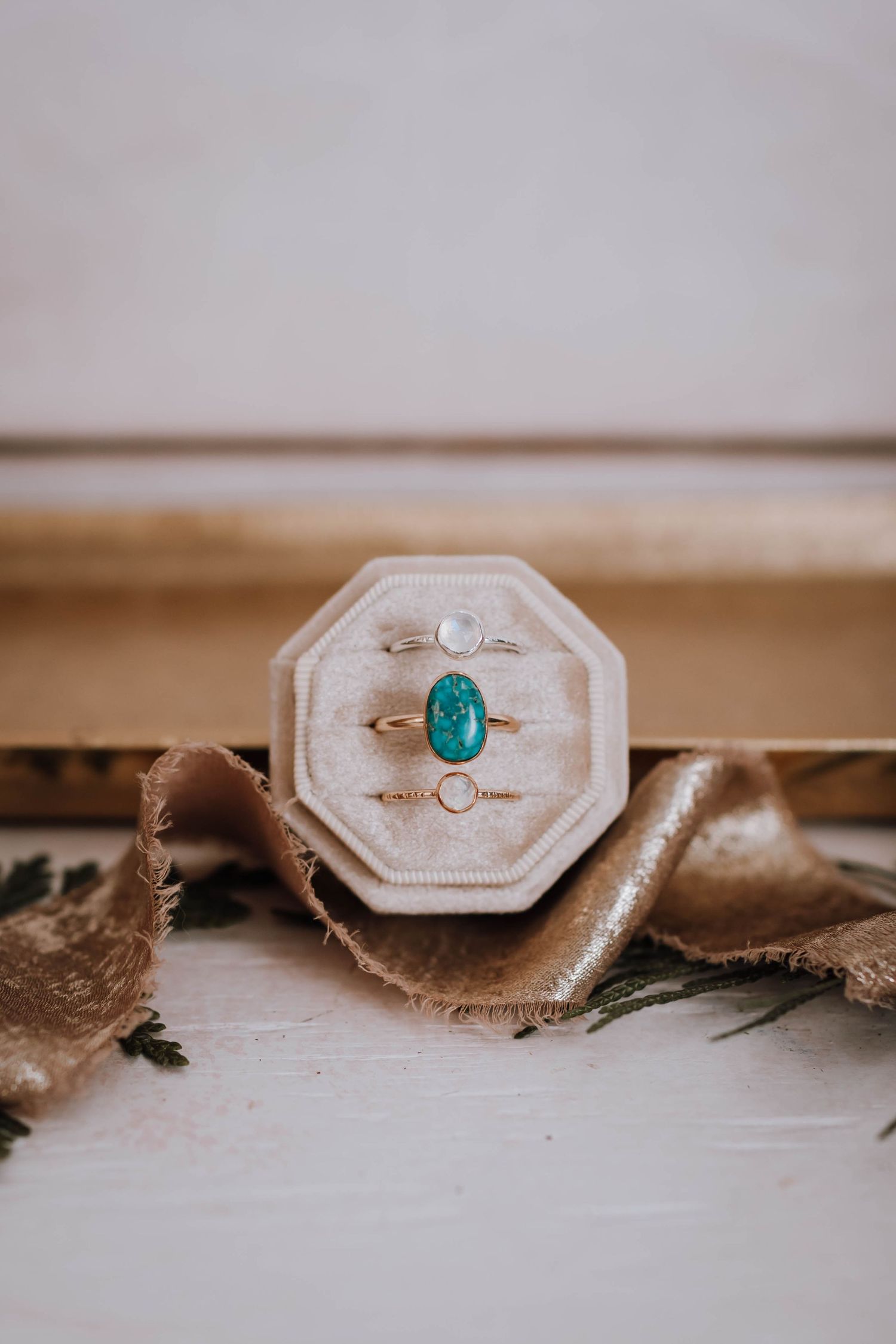 Three elegant rings displayed in octagonal velvet box with turquoise centerpiece.