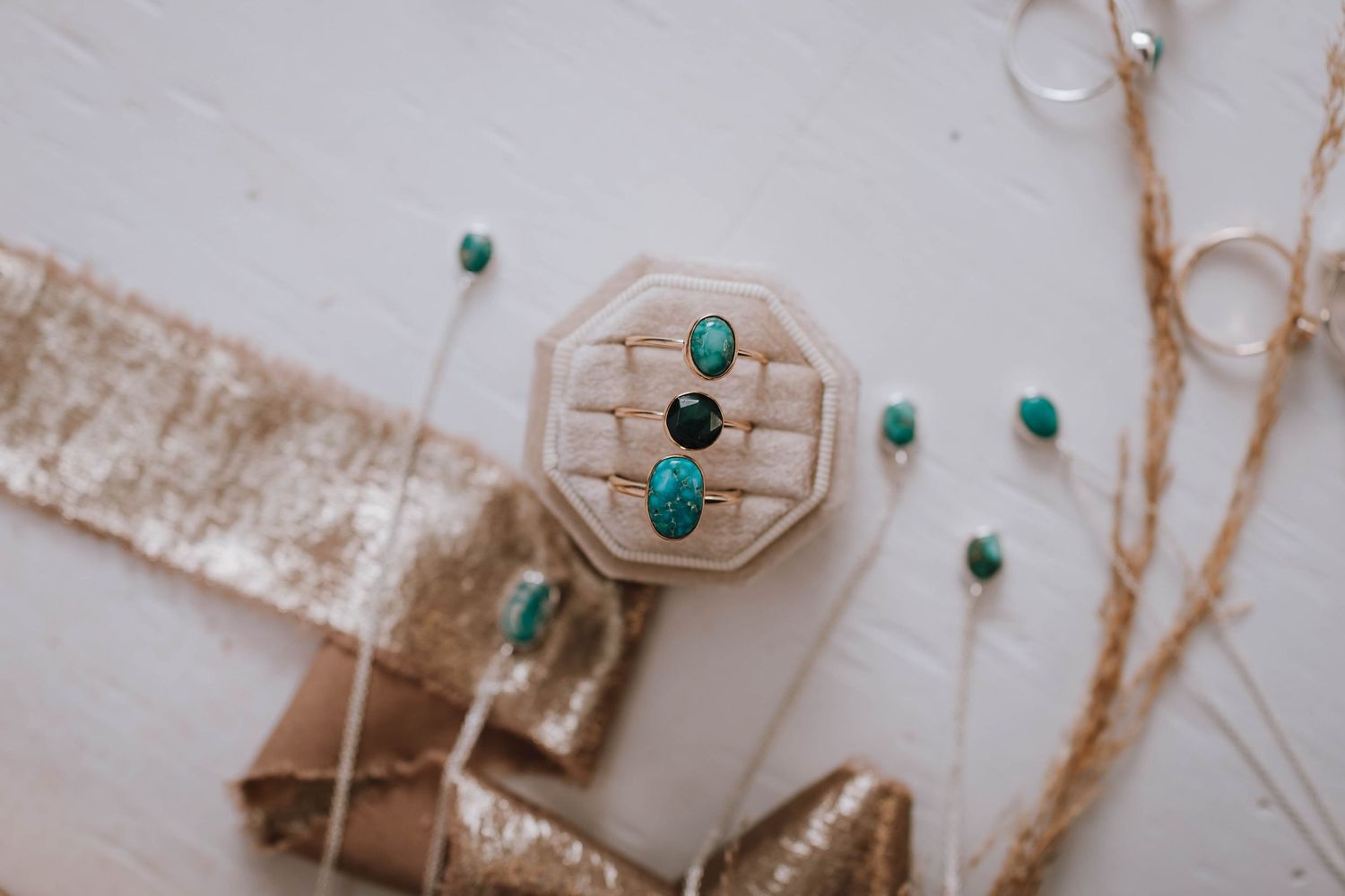 Turquoise and black gemstone rings displayed on a light-colored surface with delicate decorative elements.