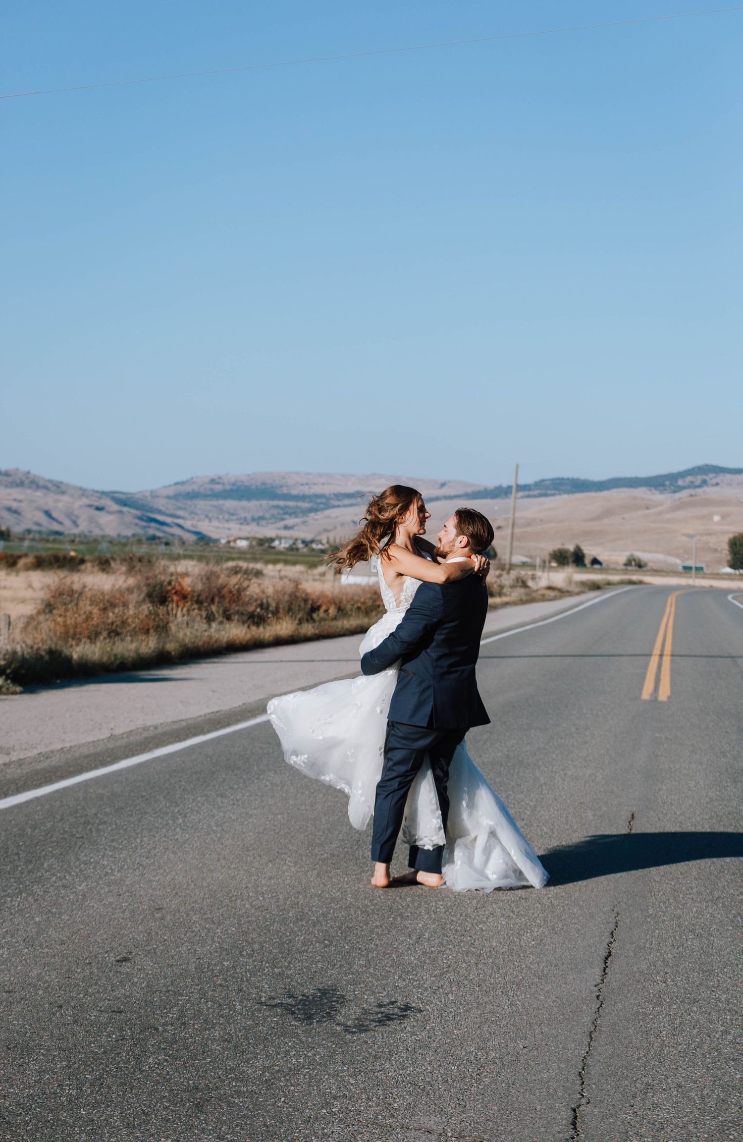 Romantic wedding dance on an empty country road with mountains in the background.