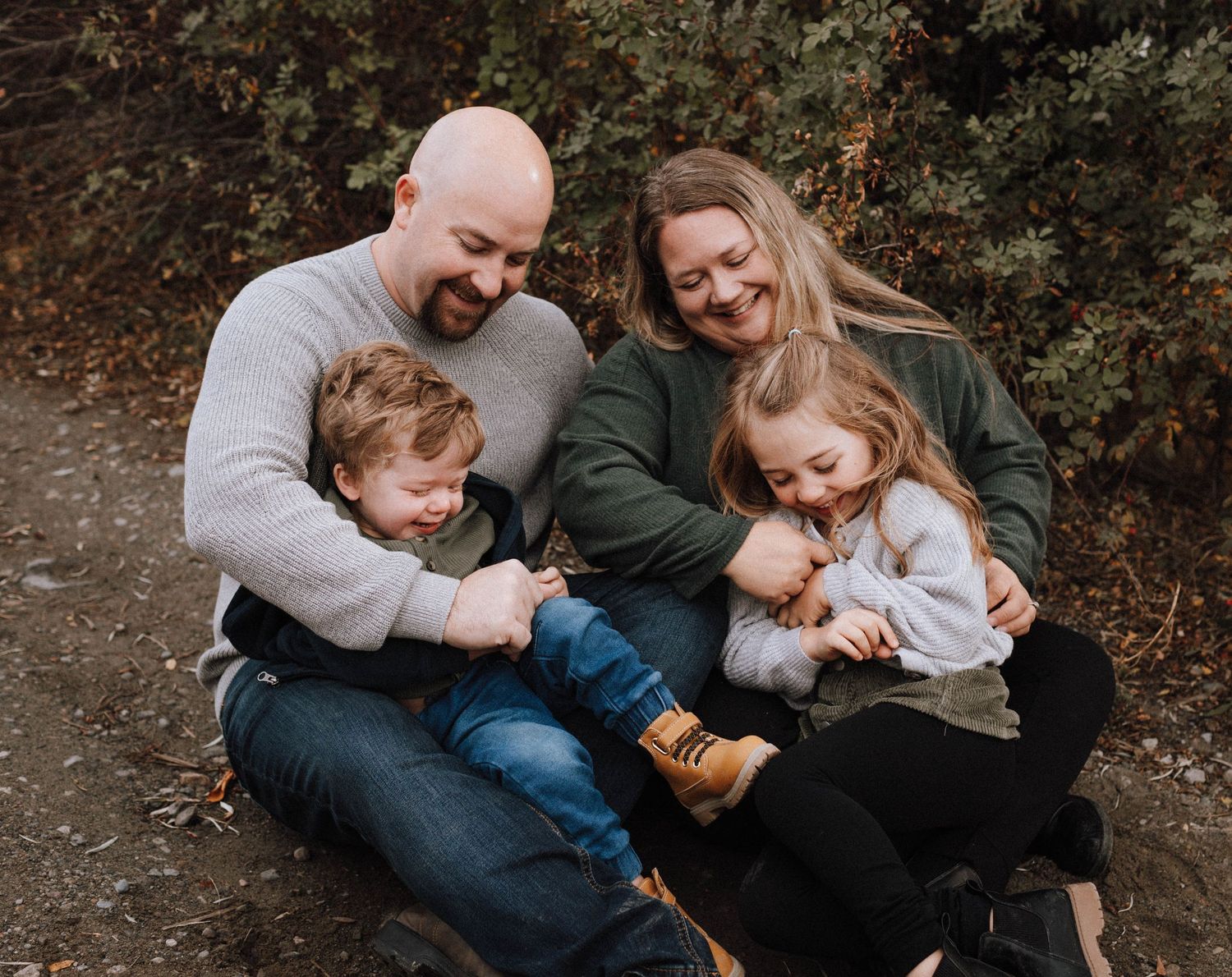 A family shares a tender moment while sitting together on a dirt path during autumn.