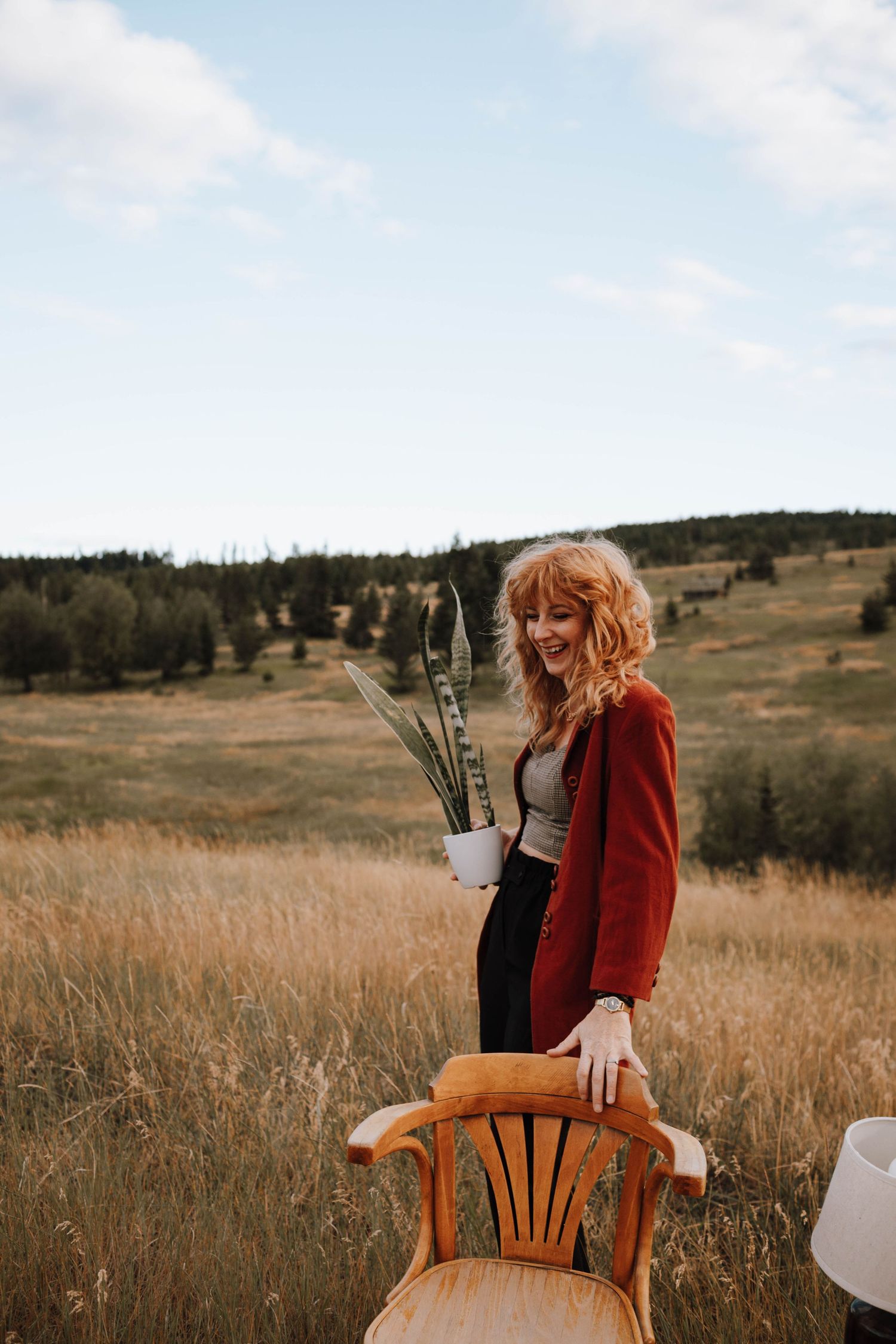 A vintage wooden chair sits in a autumn field with dried grass and distant hills.