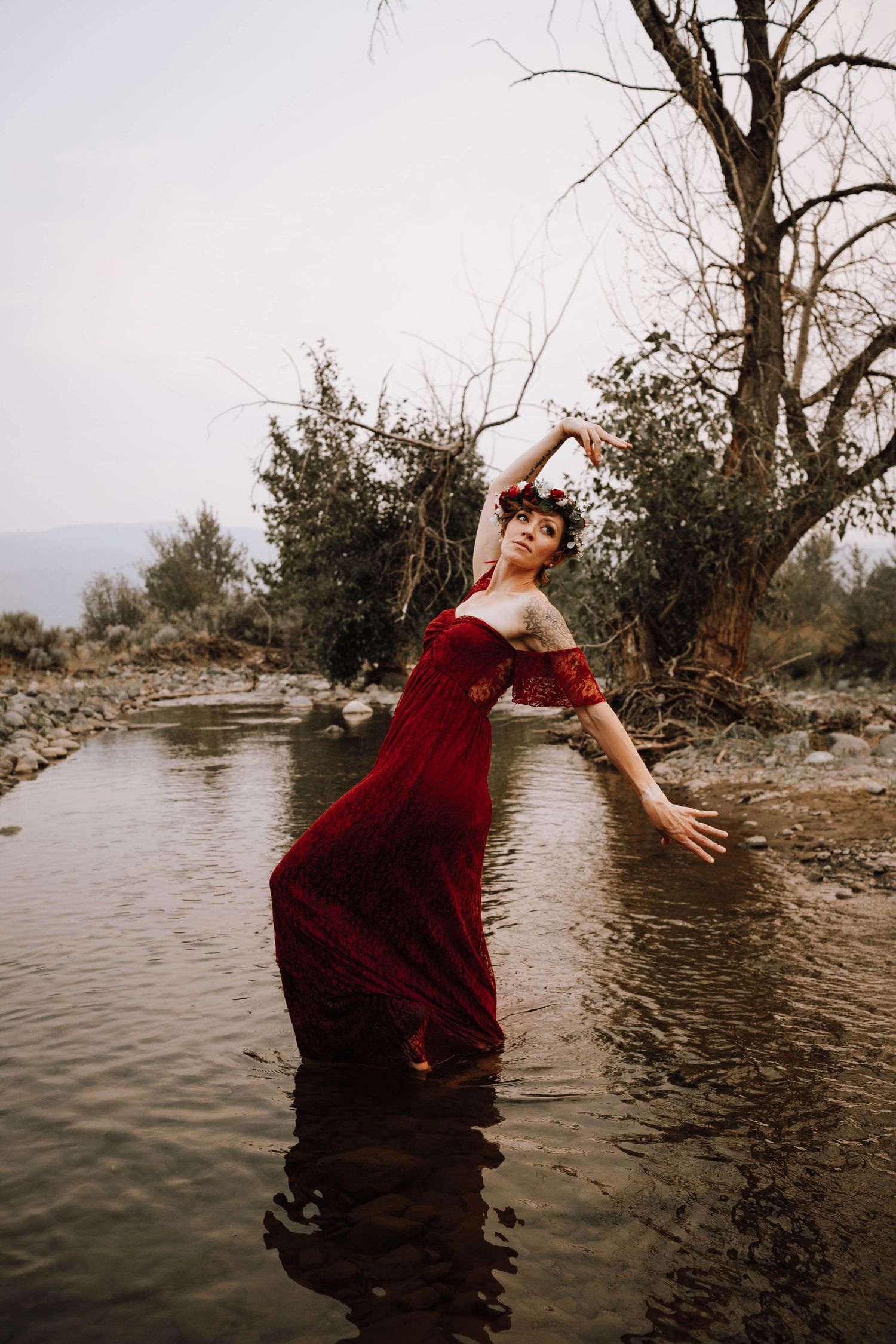 Artistic water portrait with flowing red dress in shallow river stream.