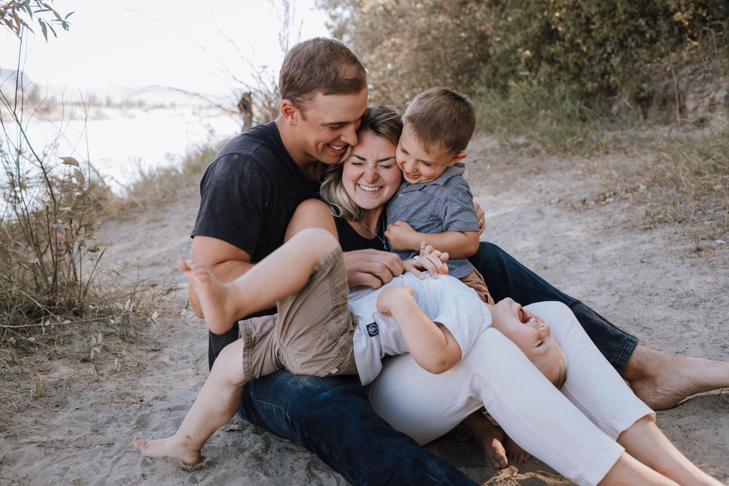 Tender family moment shared while relaxing together on a sandy trail during an outdoor photo session.