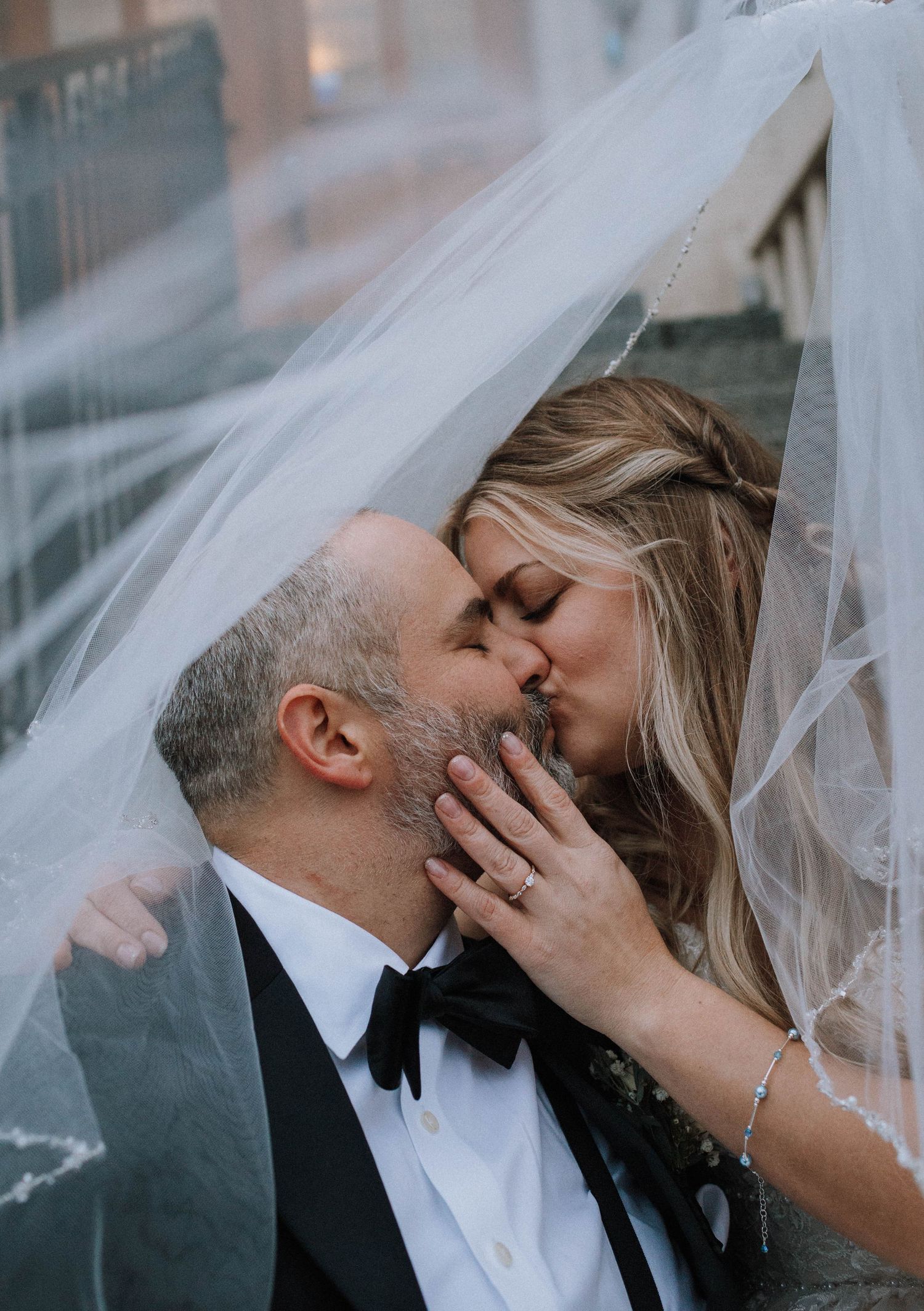 Intimate wedding portrait under flowing veil with sparkly jewelry.