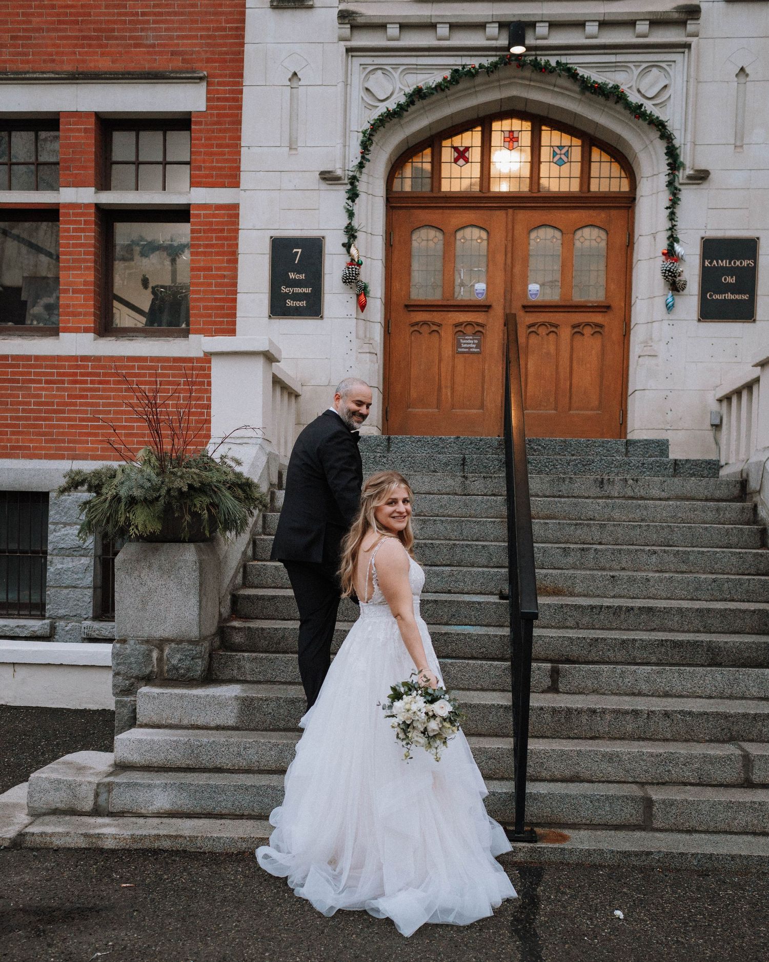 Wedding portrait on historic brick building steps with wooden door entrance.