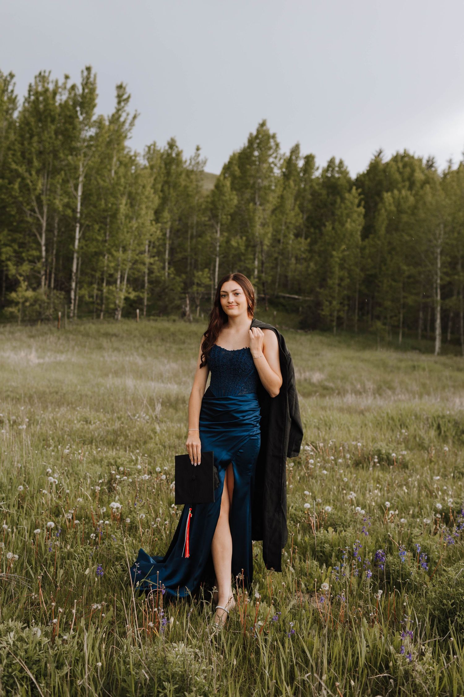 A dark blue evening dress worn in a meadow with aspen trees in the background.
