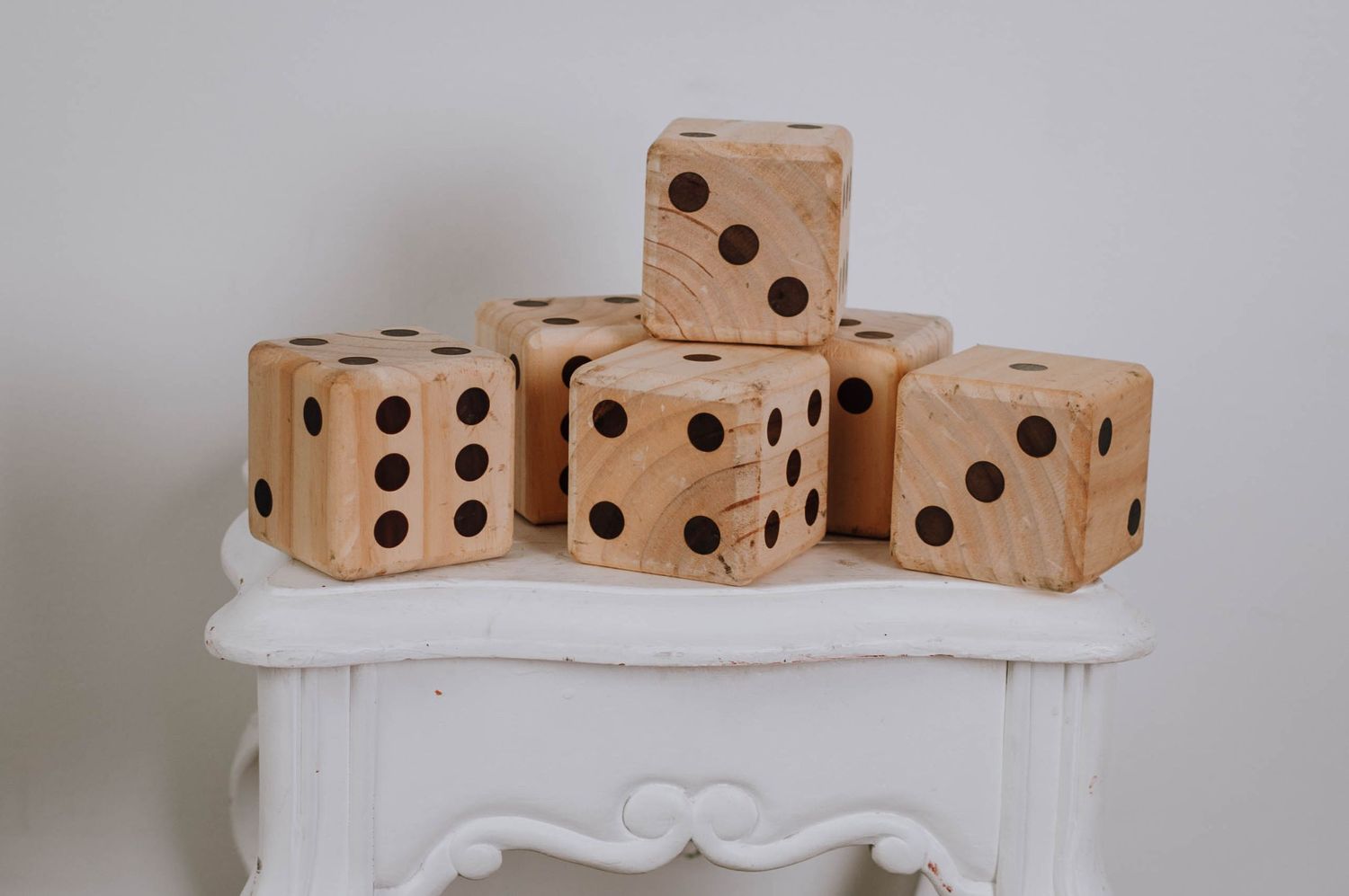 Four wooden dice with black dots displayed on white decorative surface.