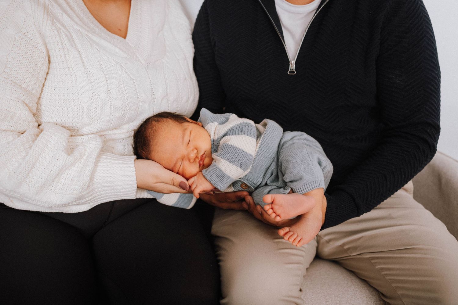Newborn baby sleeping on parent's lap in comfortable home setting.