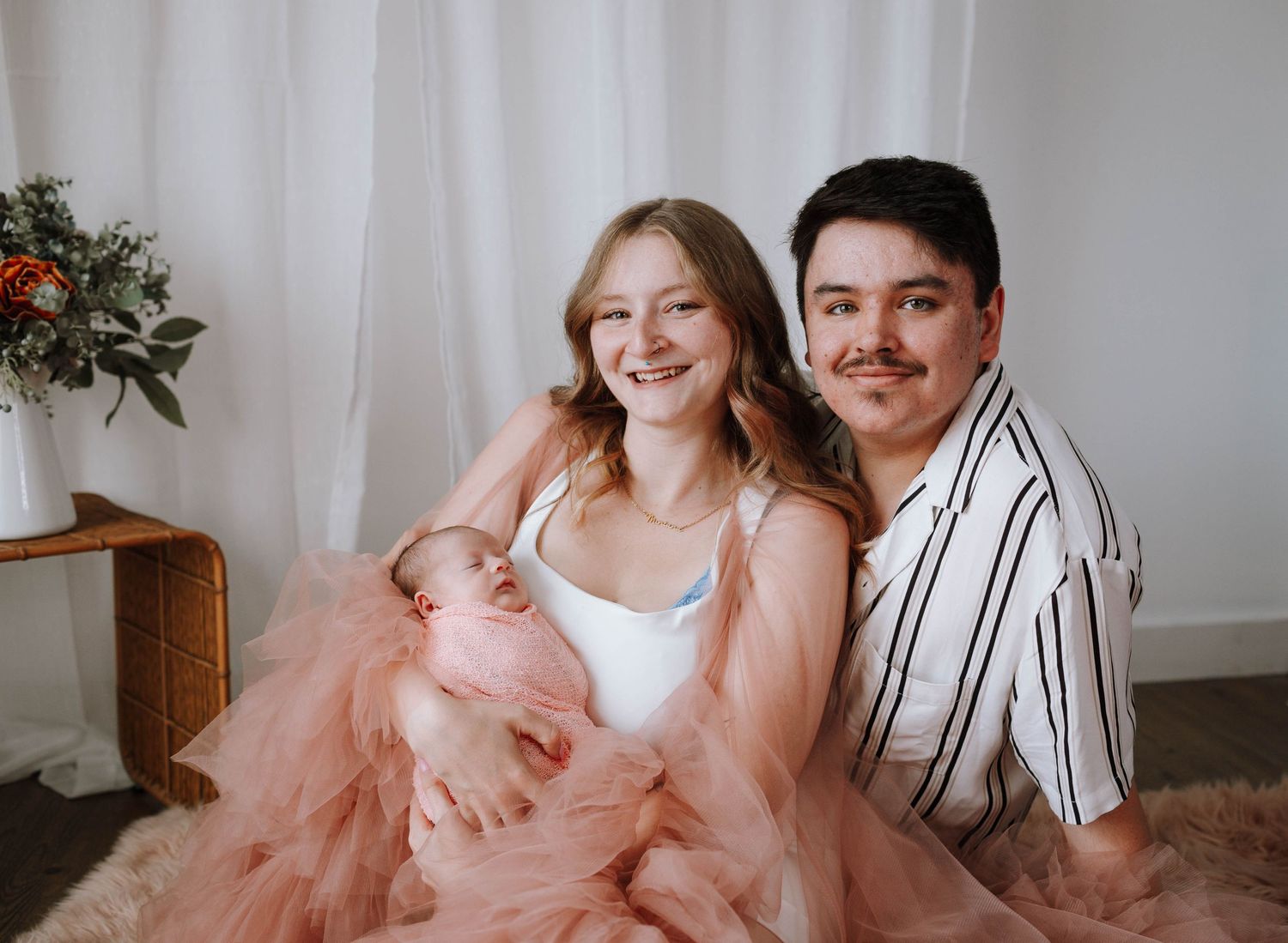 Happy couple posing together in elegant pink and white outfits.