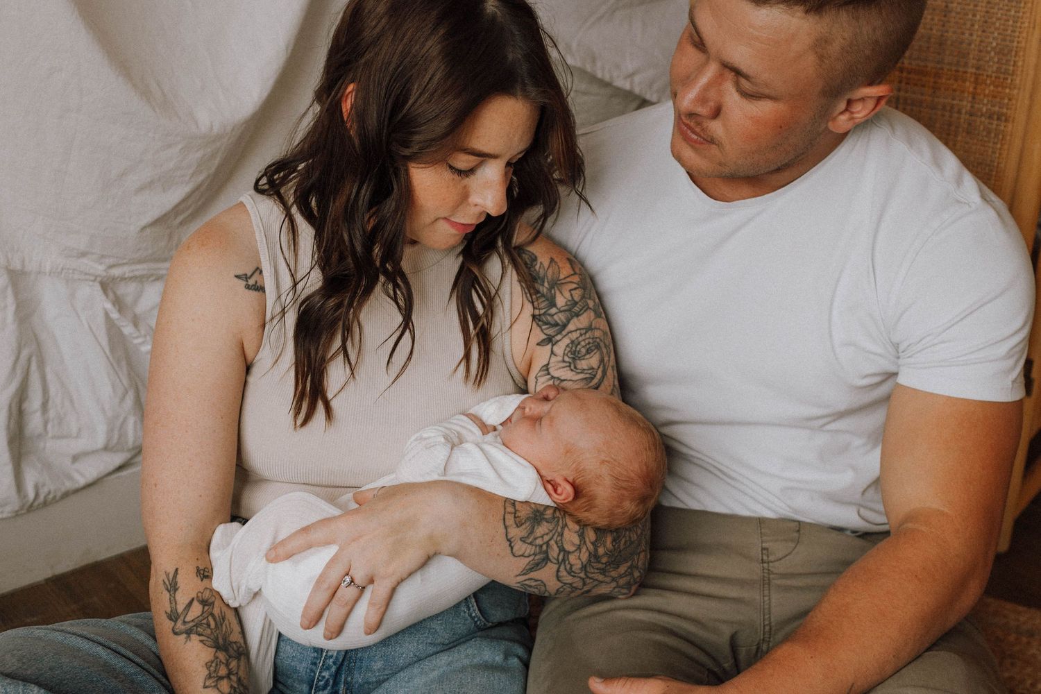 Tender lifestyle family photo series showing intimate moments between parents and newborn baby in muted neutral tones.