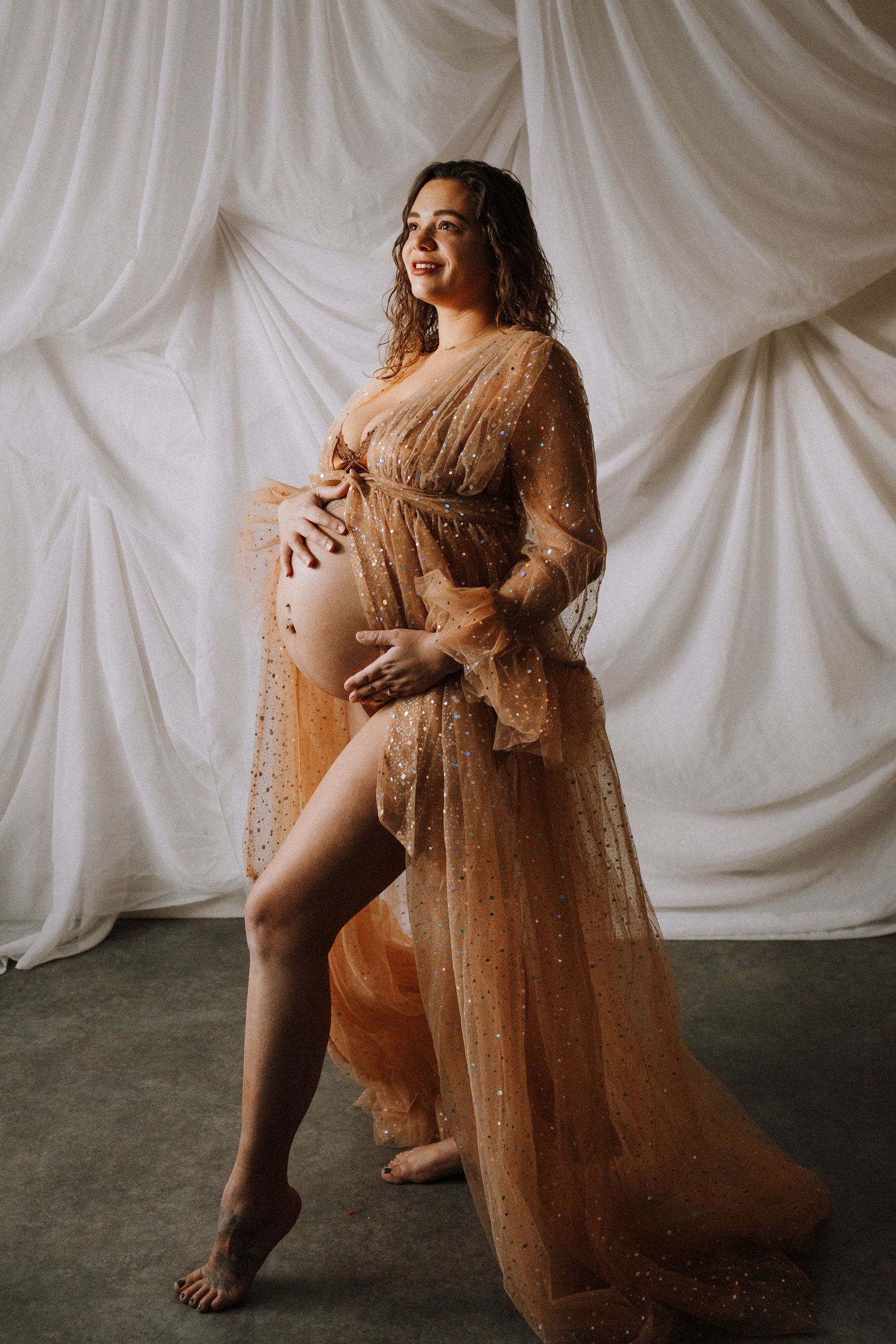 Artistic portrait series against white backdrop featuring flowing sheer copper-colored dress in dramatic poses.