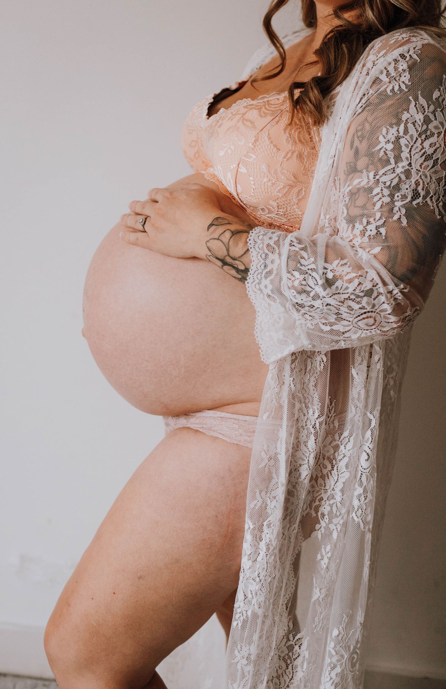 Side profile of a pregnant belly wearing delicate lace lingerie.