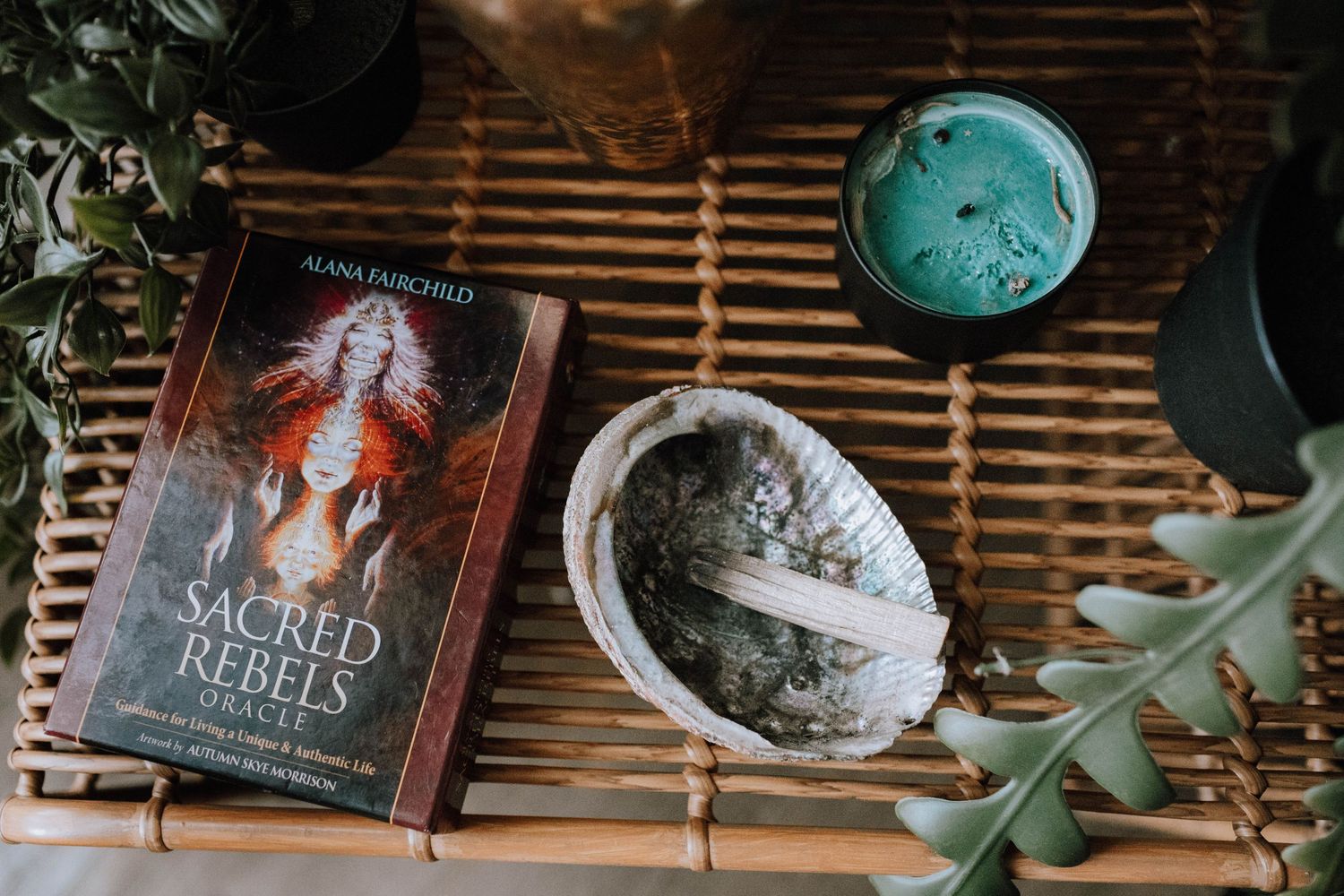 Still life with Red Queen book, turquoise ornament, and decorative bowl on bamboo surface.