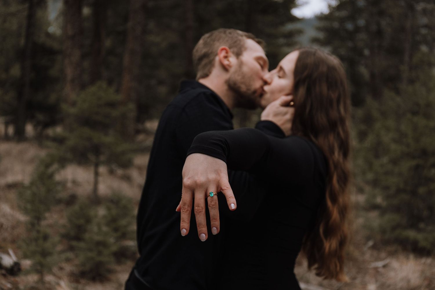A romantic couple embraces in a forest setting during a photo session at sunset.