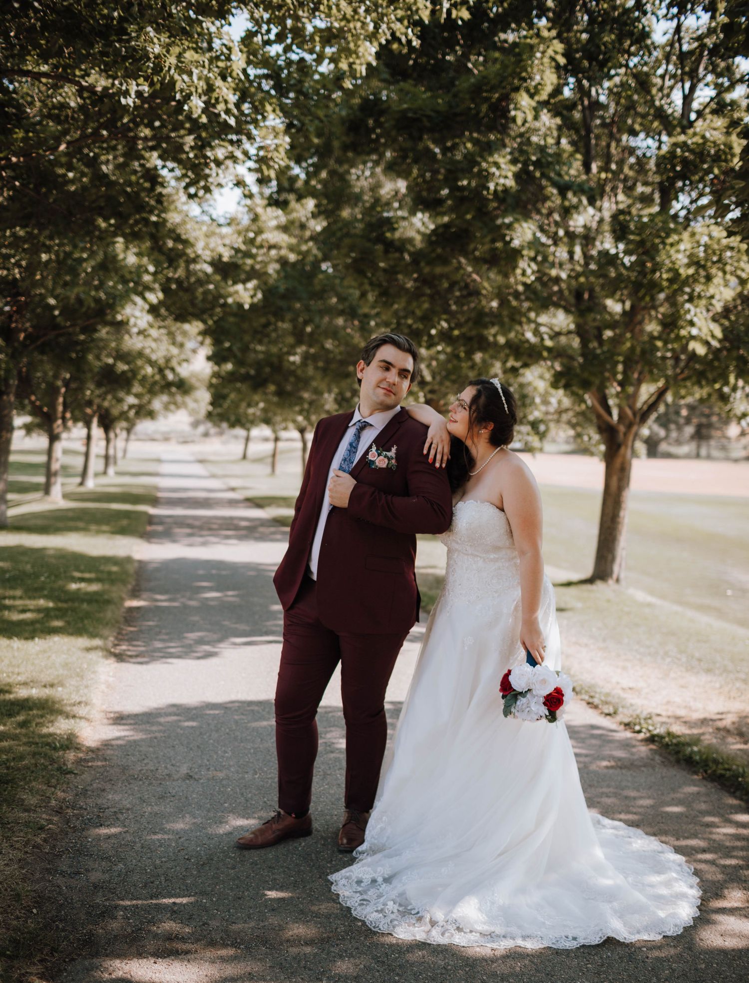 A playful wedding portrait of a couple on a tree-lined path.