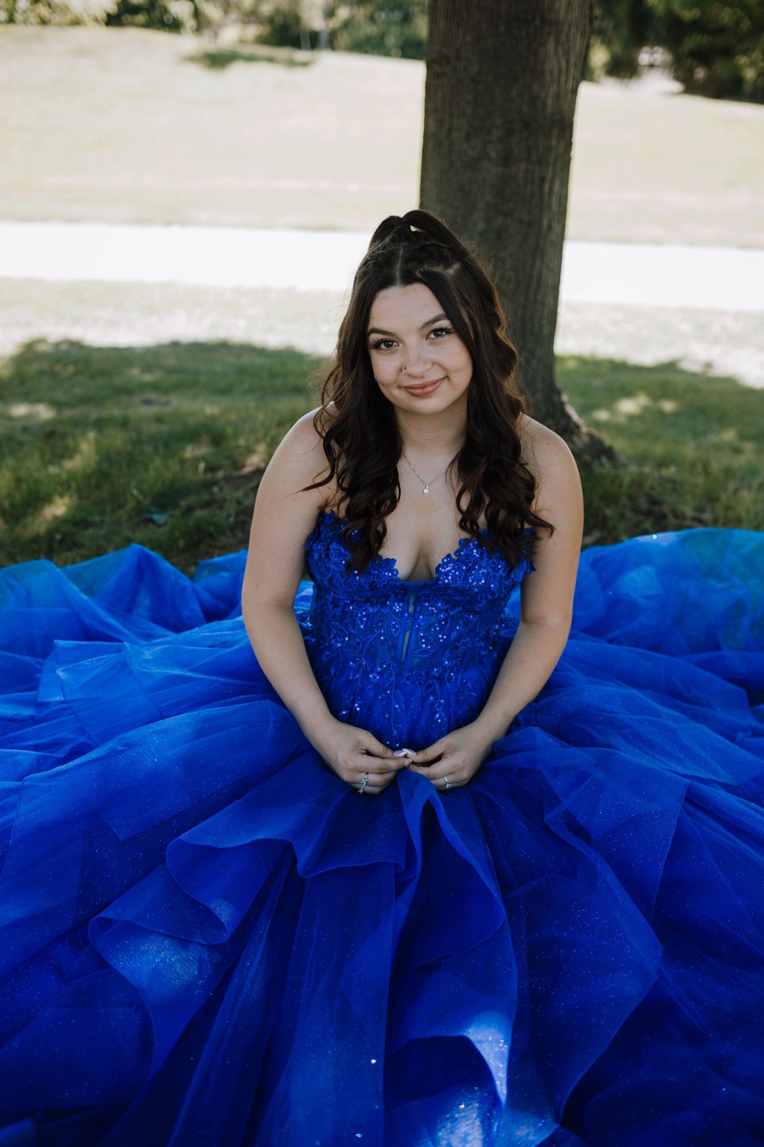 A stunning royal blue ballgown with intricate beading and layers of tulle photographed outdoors.