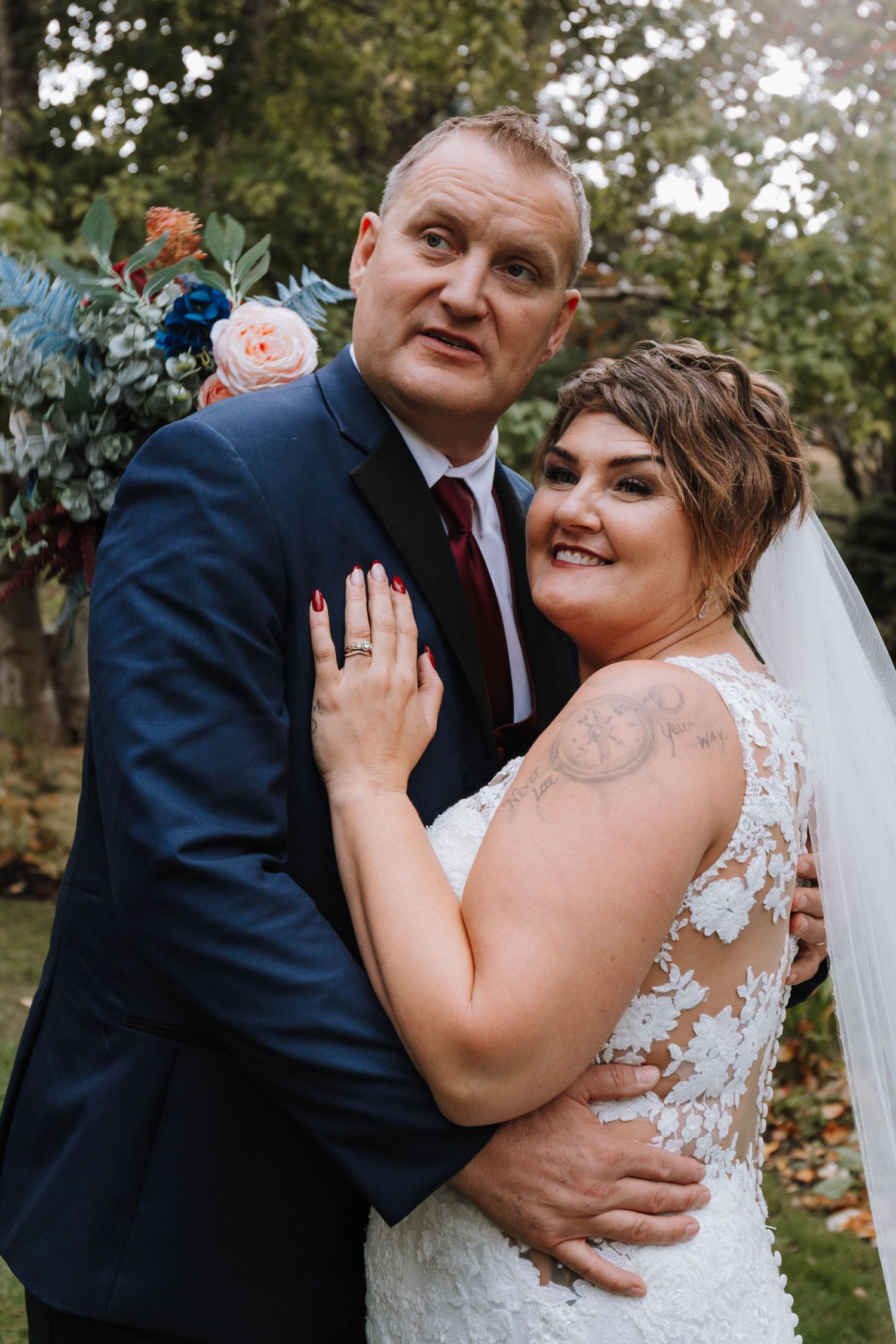 Wedding portrait with lush floral arrangements featuring pink and blue blooms.