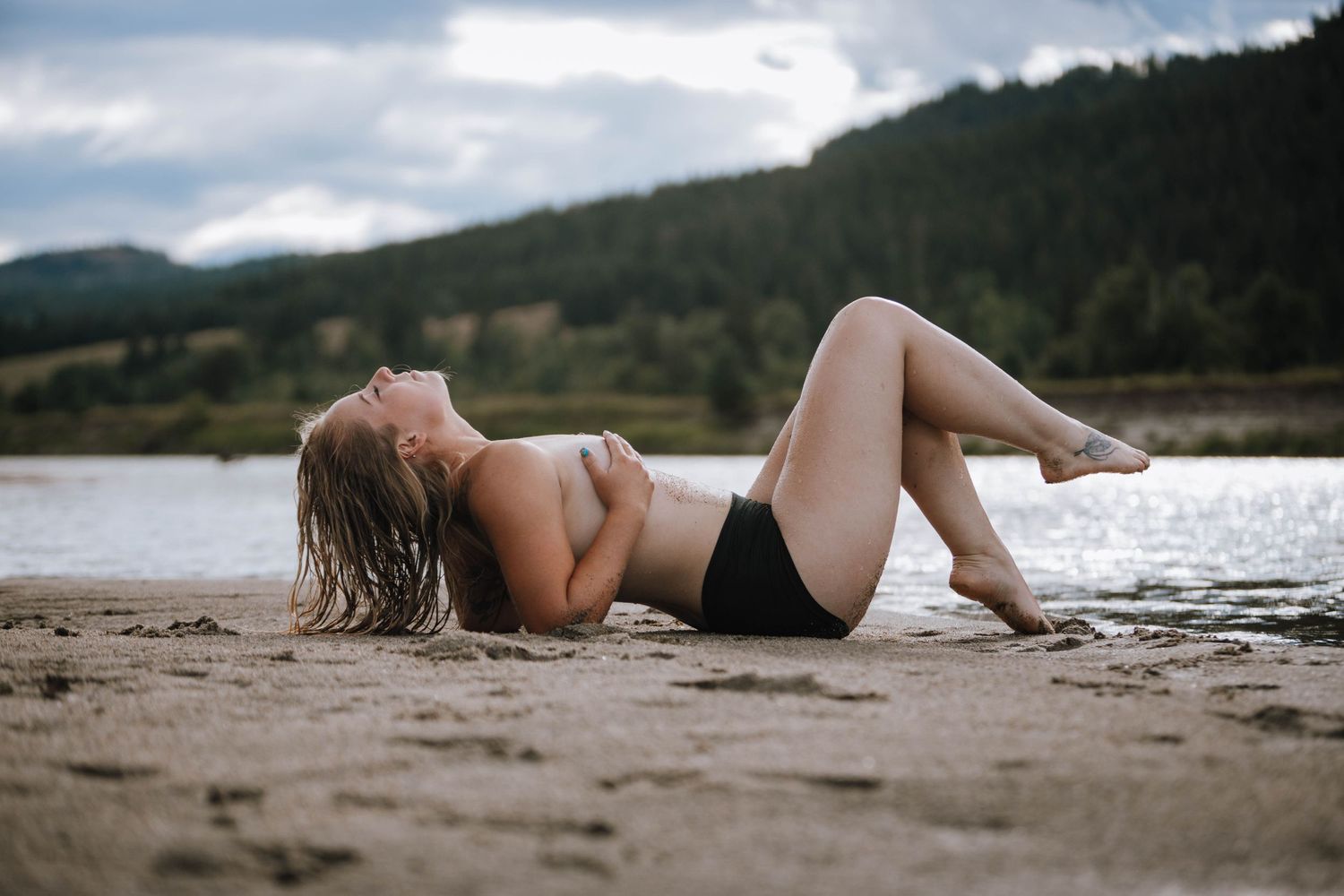 Summer beach portrait with mountains and cloudy sky in background.