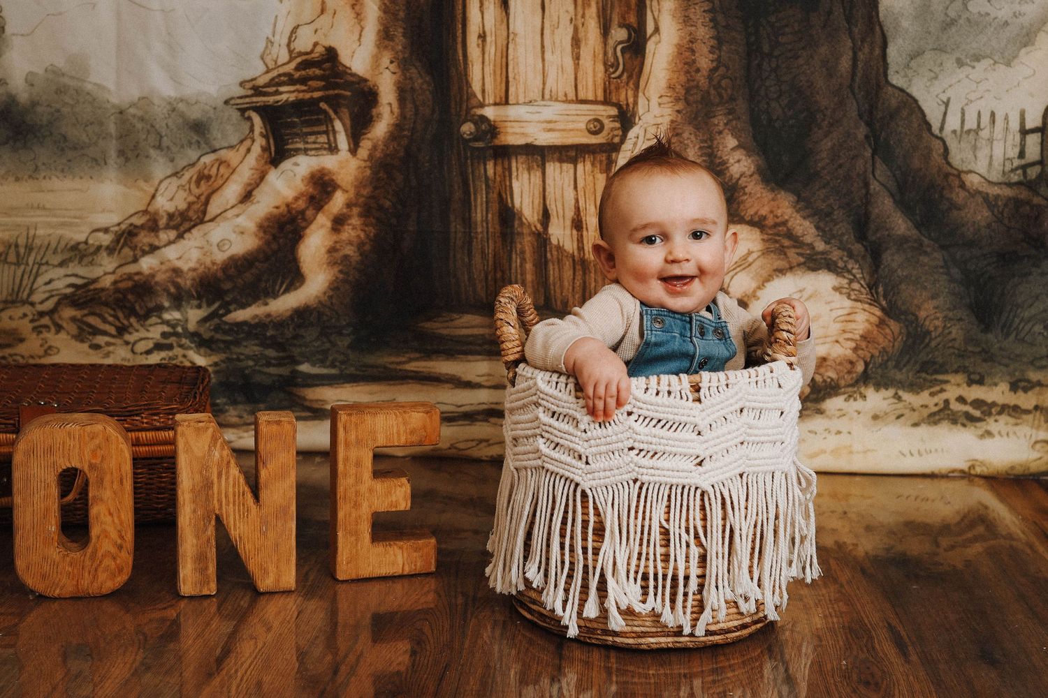 Baby sitting in macrame swing with rustic ONE letters for first birthday photoshoot.