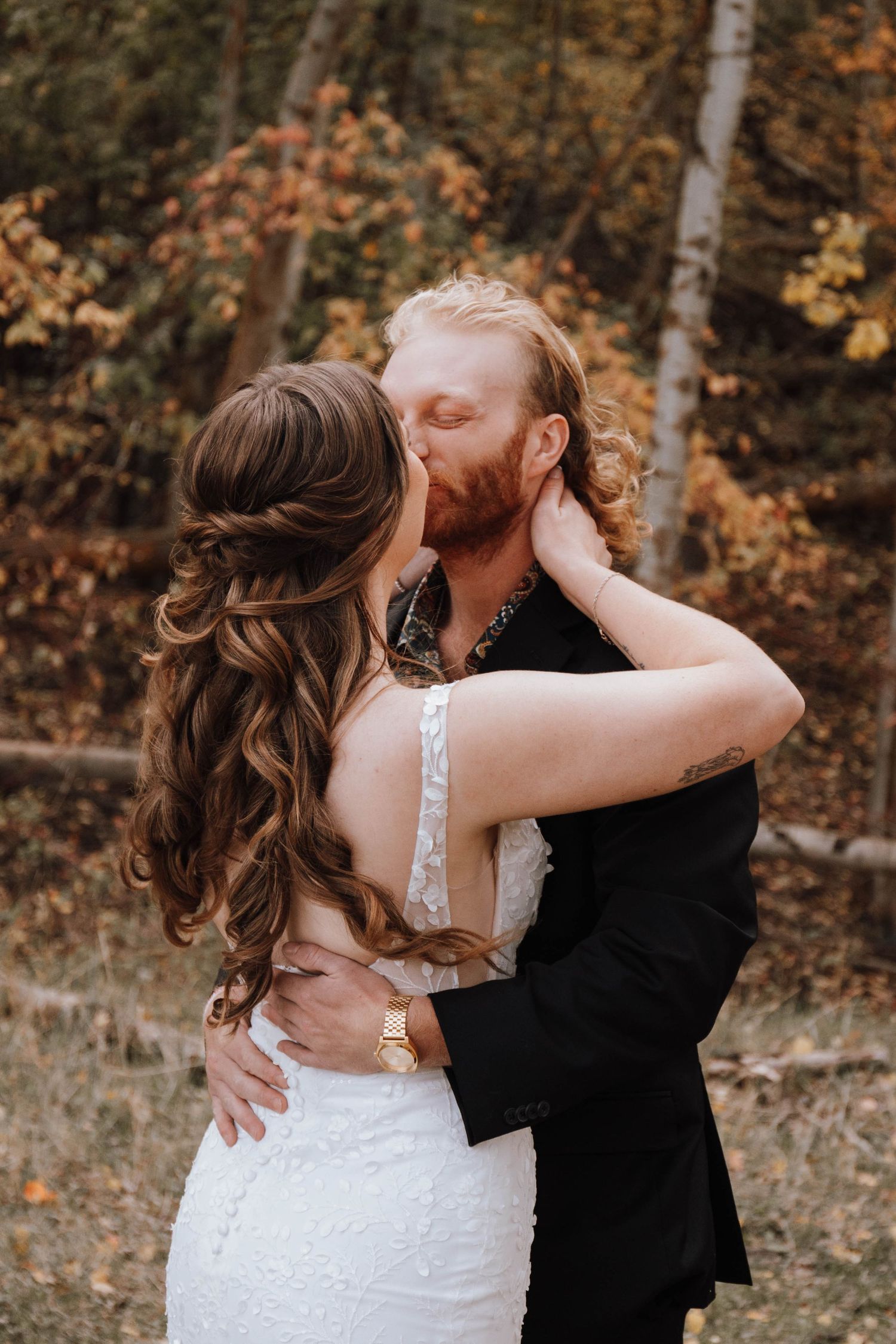 A romantic embrace between newlyweds surrounded by fall foliage.