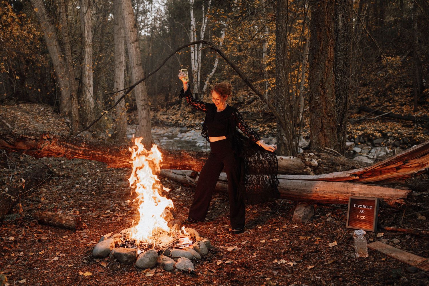 A series of nighttime images showing a campfire burning in a wooded area with fallen leaves on the ground.