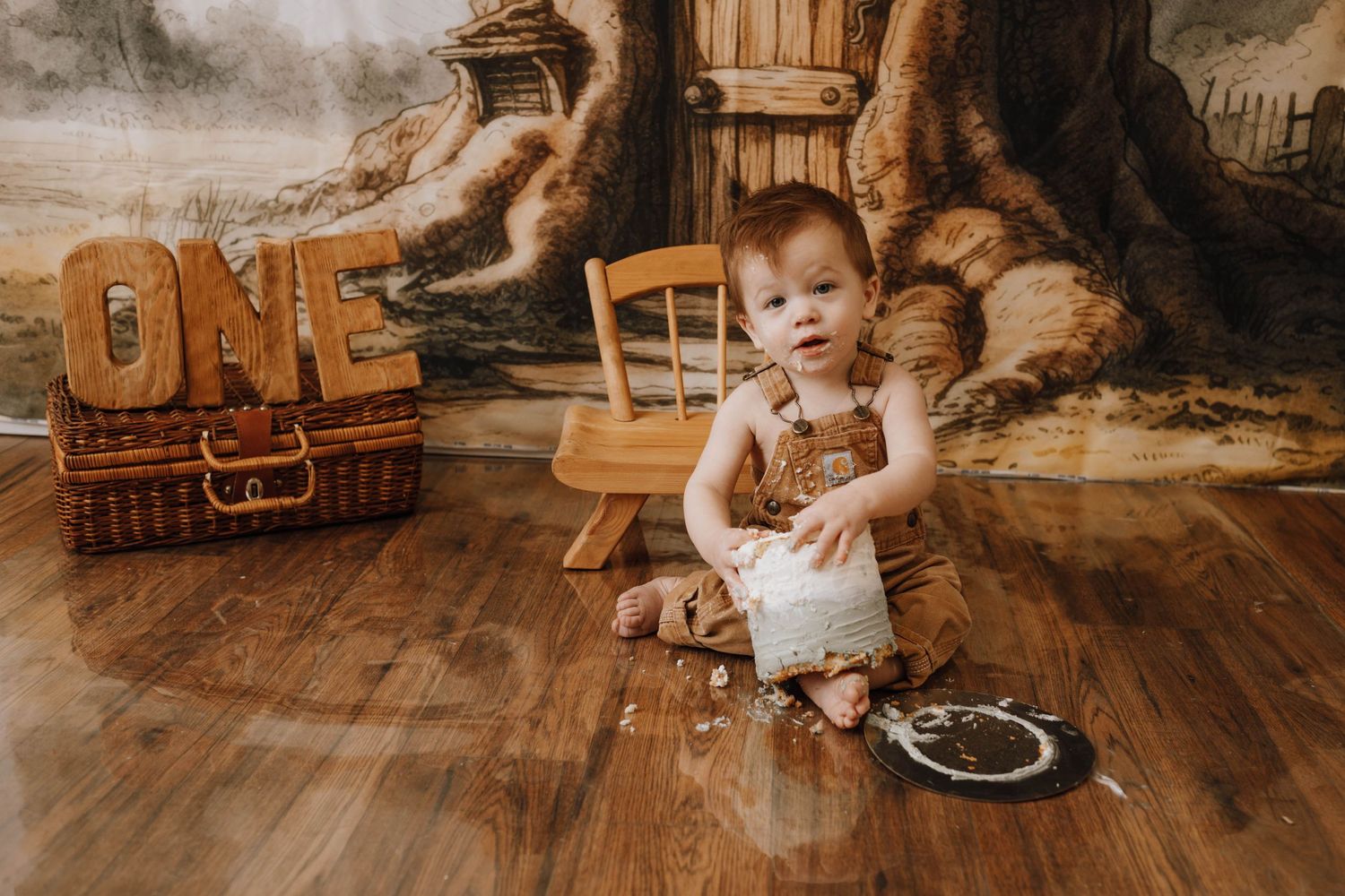 First birthday setup with rustic wooden ONE letters and baby on hardwood floor.