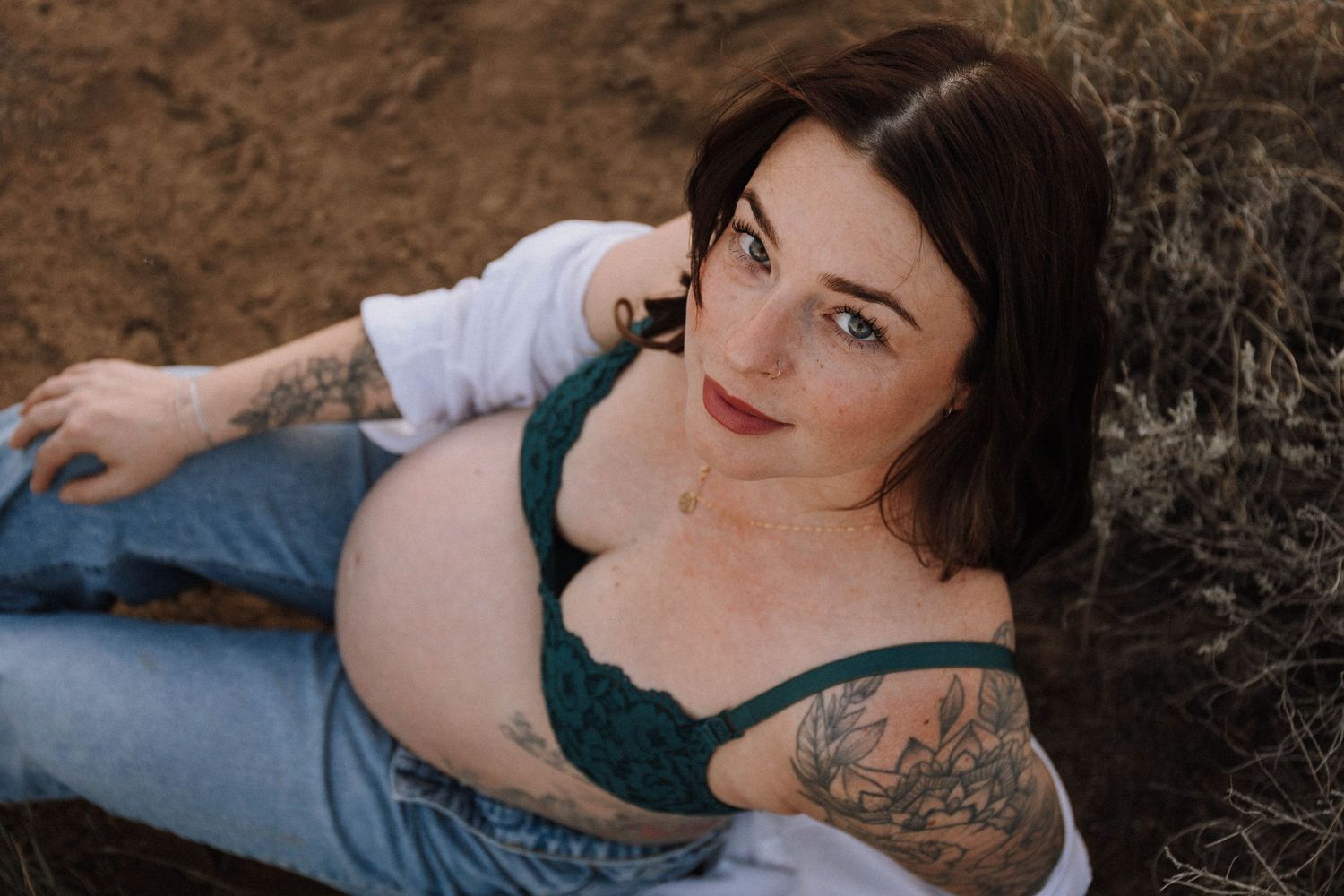 A series of intimate maternity portrait photographs showing a pregnant woman lying in tall brown grass outdoors.