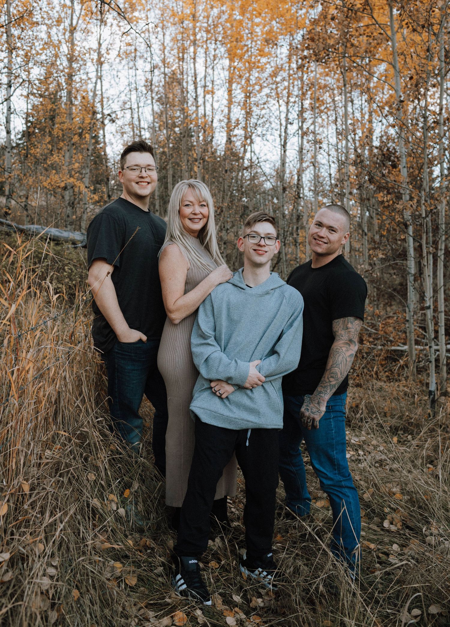 A group poses together in a wooded area during autumn with golden aspen trees in the background.