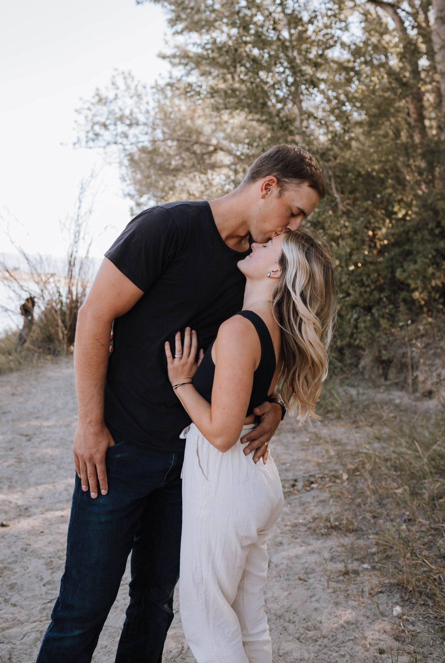 Romantic embrace captured in golden afternoon light on nature path.